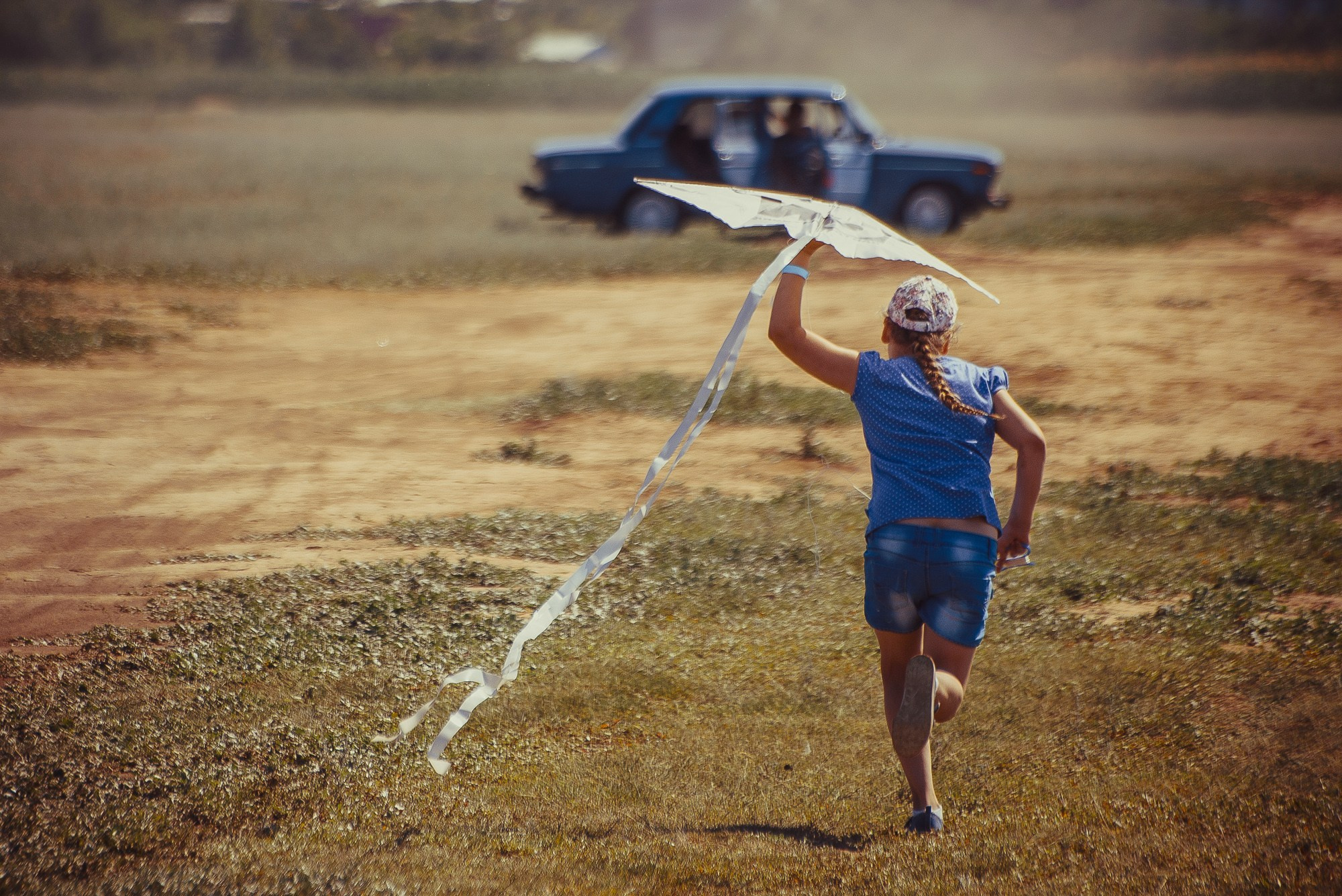 Девочка бежит вдаль, запуская воздушный змей