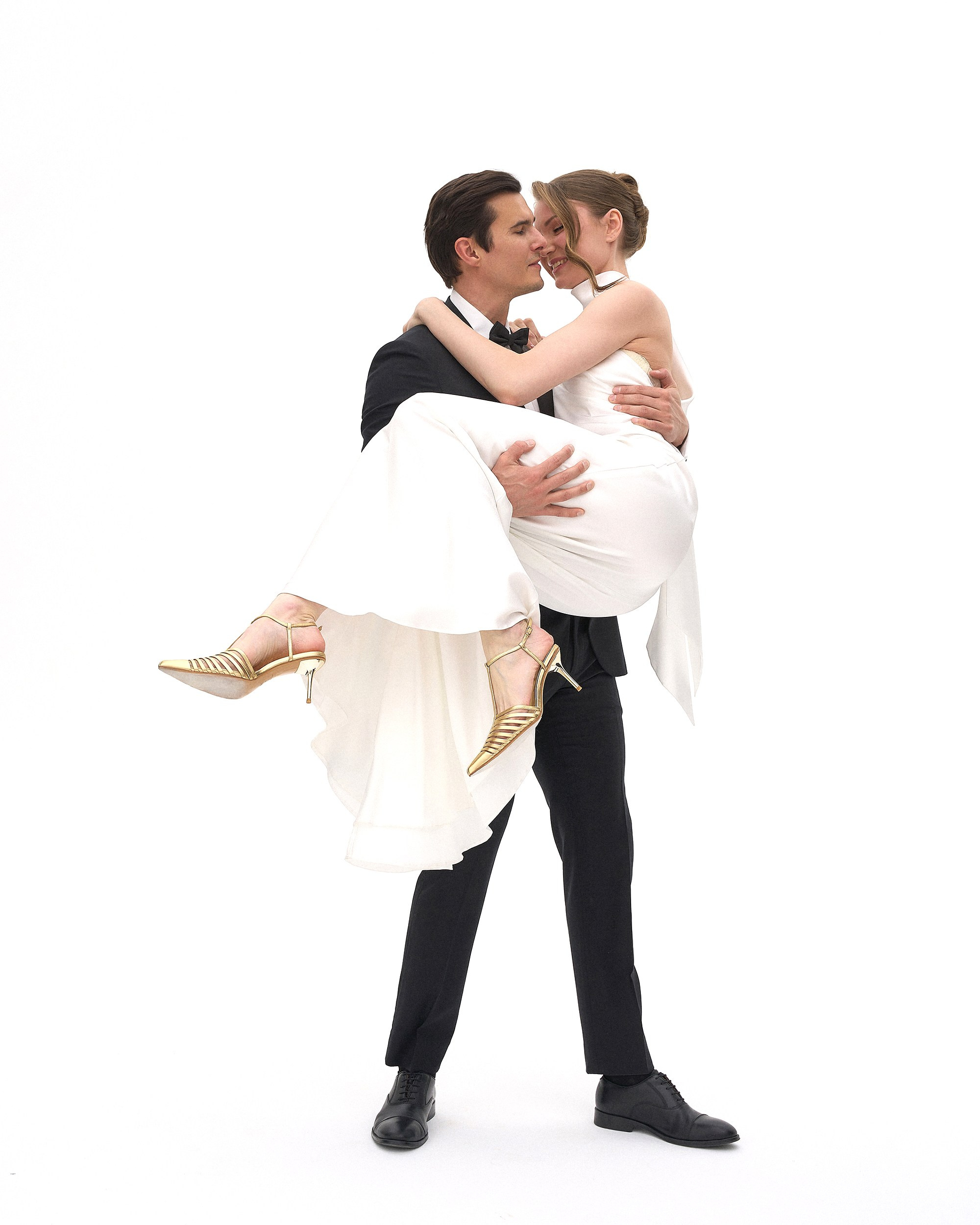 Невеста на руках у жениха, пара смеётся и смотрит друг на друга, белый фон, студийный портрет на свадьбу, фотограф Дмитрий Цветков, СПб