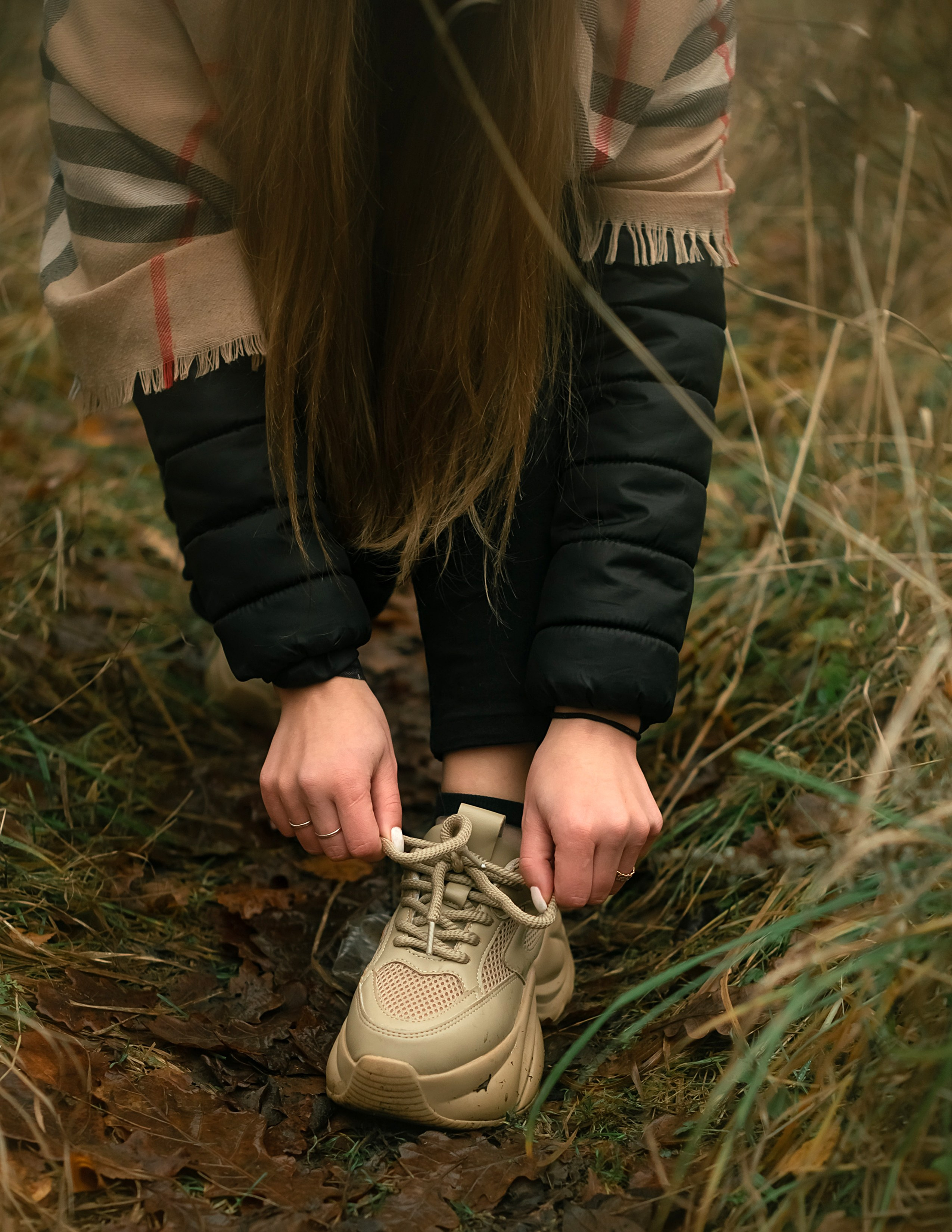 На фото девушка поправляет шнурки ботинка.