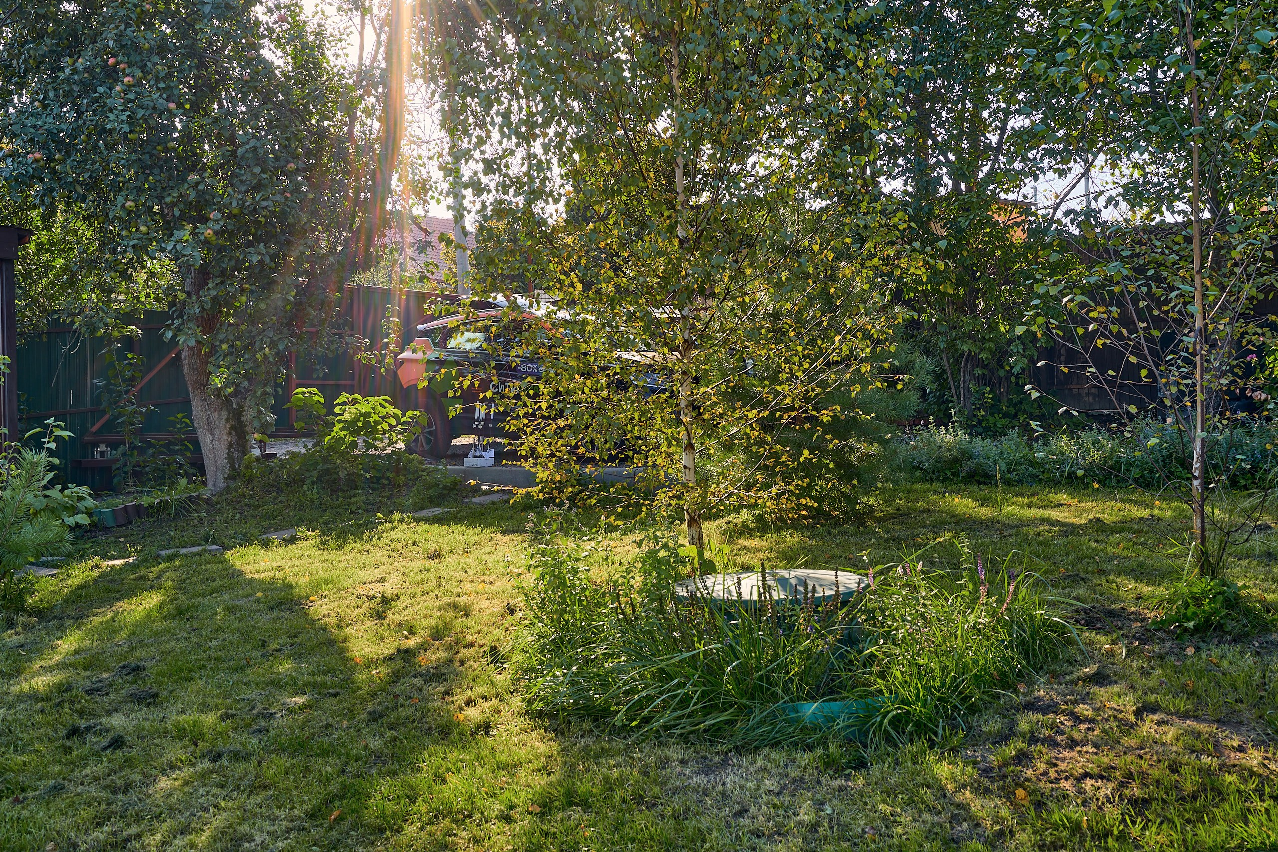 Архитектурная съемка на земельном участке загородного дома в Московской области с золотым закатным лучом и автомобилем на собственной парковке