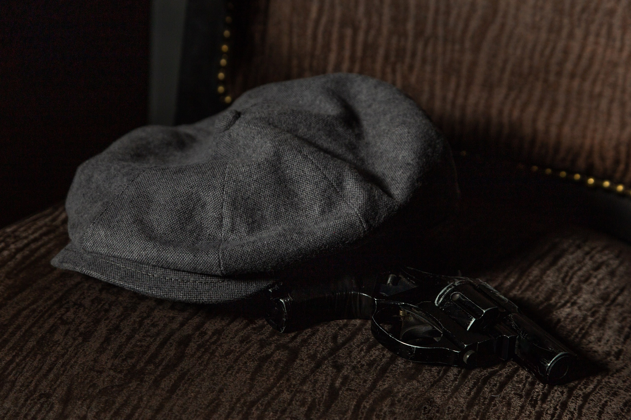 Кепка и револьвер как в сериале Острые козырьки лежат на деревянном столе.