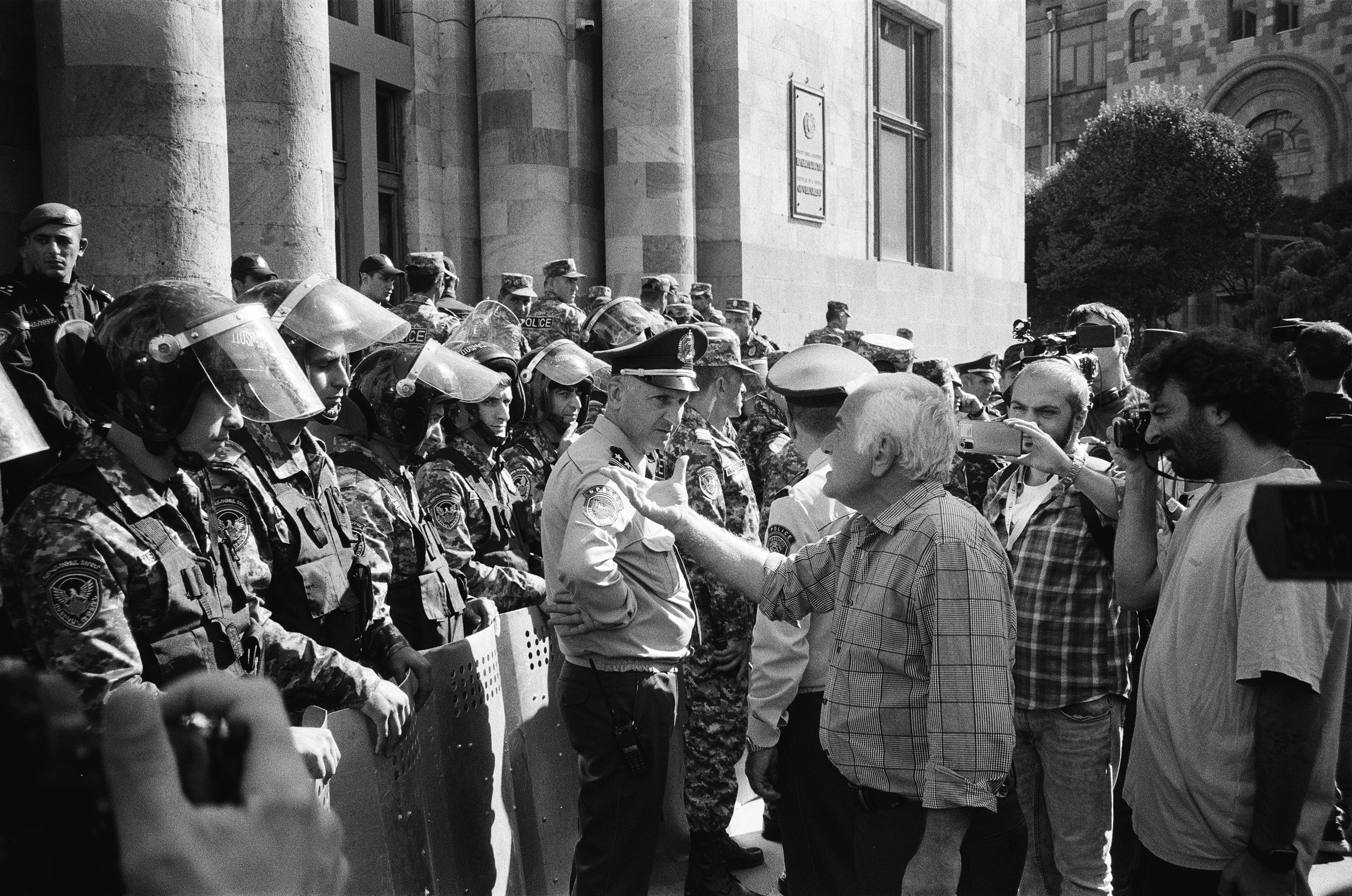 The protesters are arguing with the police in front of the government building at Republic Square.