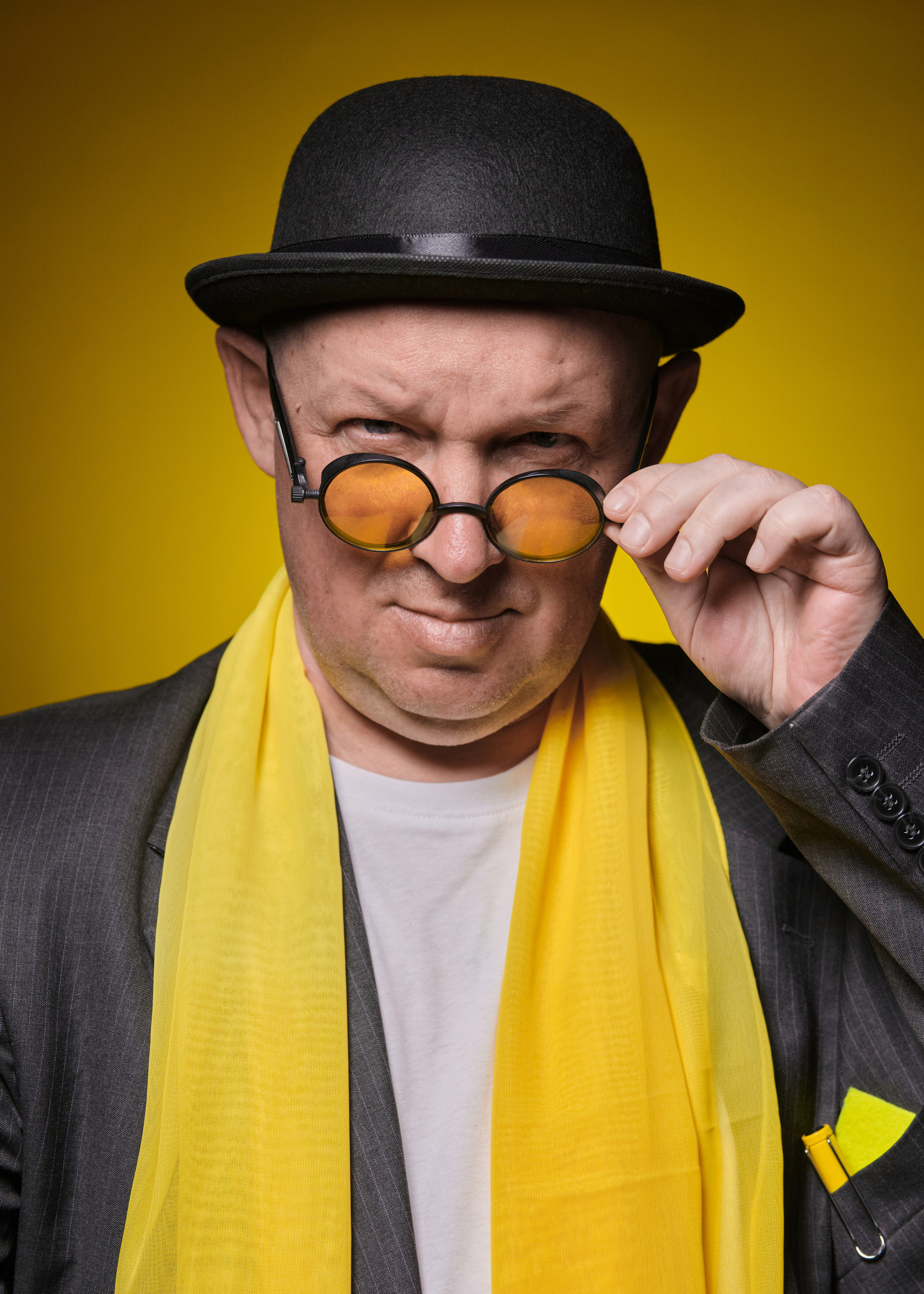 Творческий студийный портрет мужчины в котелке, желтом шарфе и очках с задумчивым, выразительным взглядом | Художественная фотосессия для личного бренда или портфолио артиста