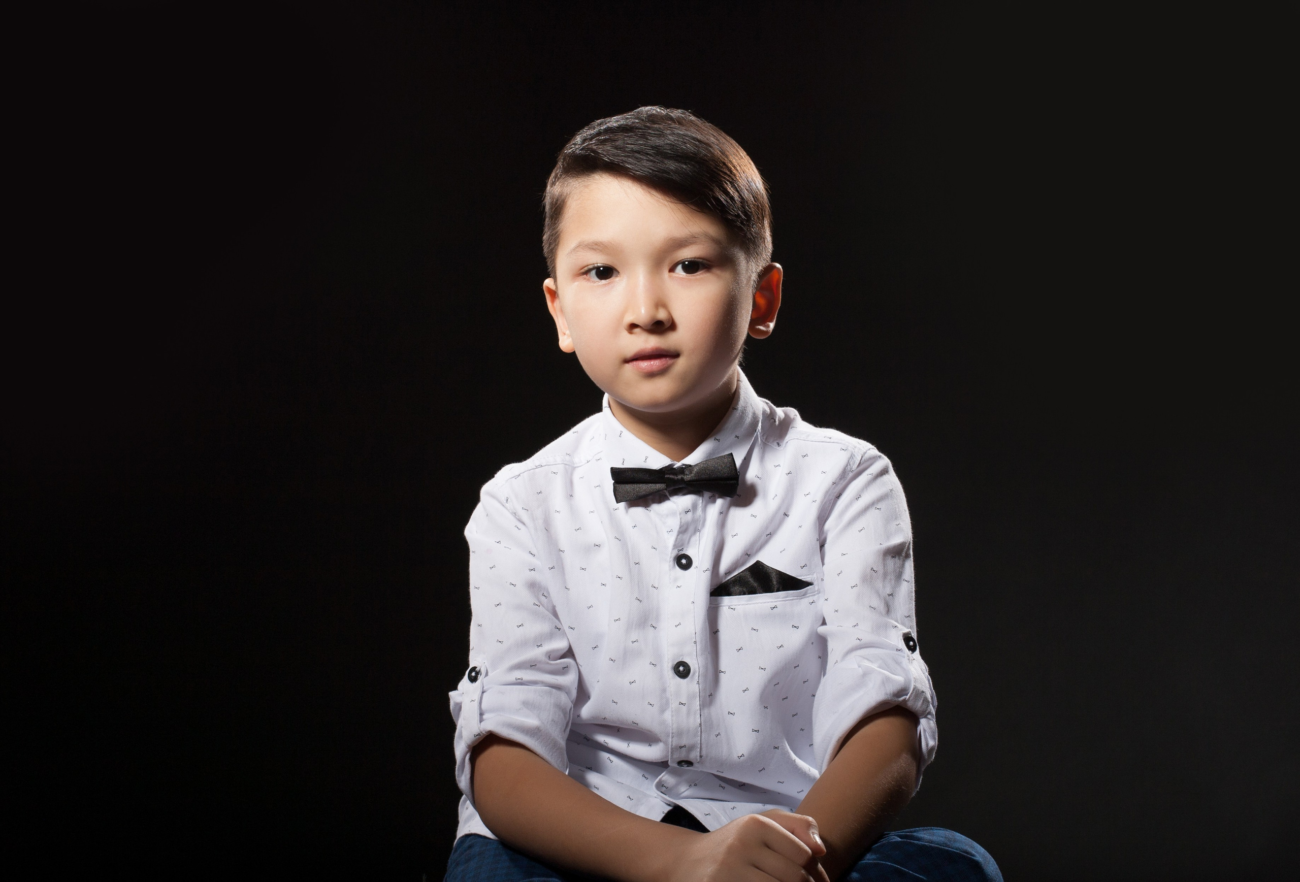 Детский портрет Алматы. Мальчик в белой рубашке на темном фоне.