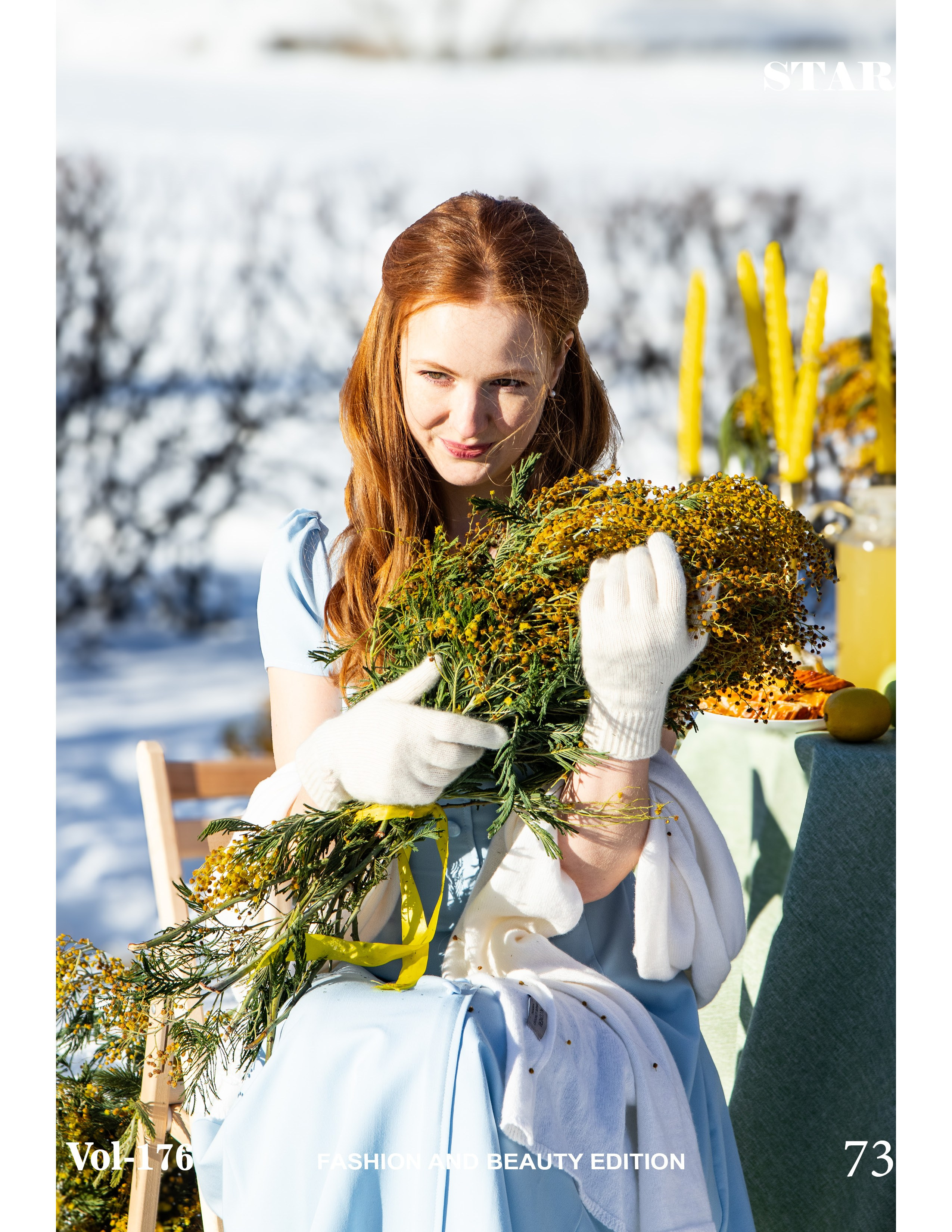 Женщина сидит на снегу, обнимая букет мимозы, глаза жмурятся на солнце