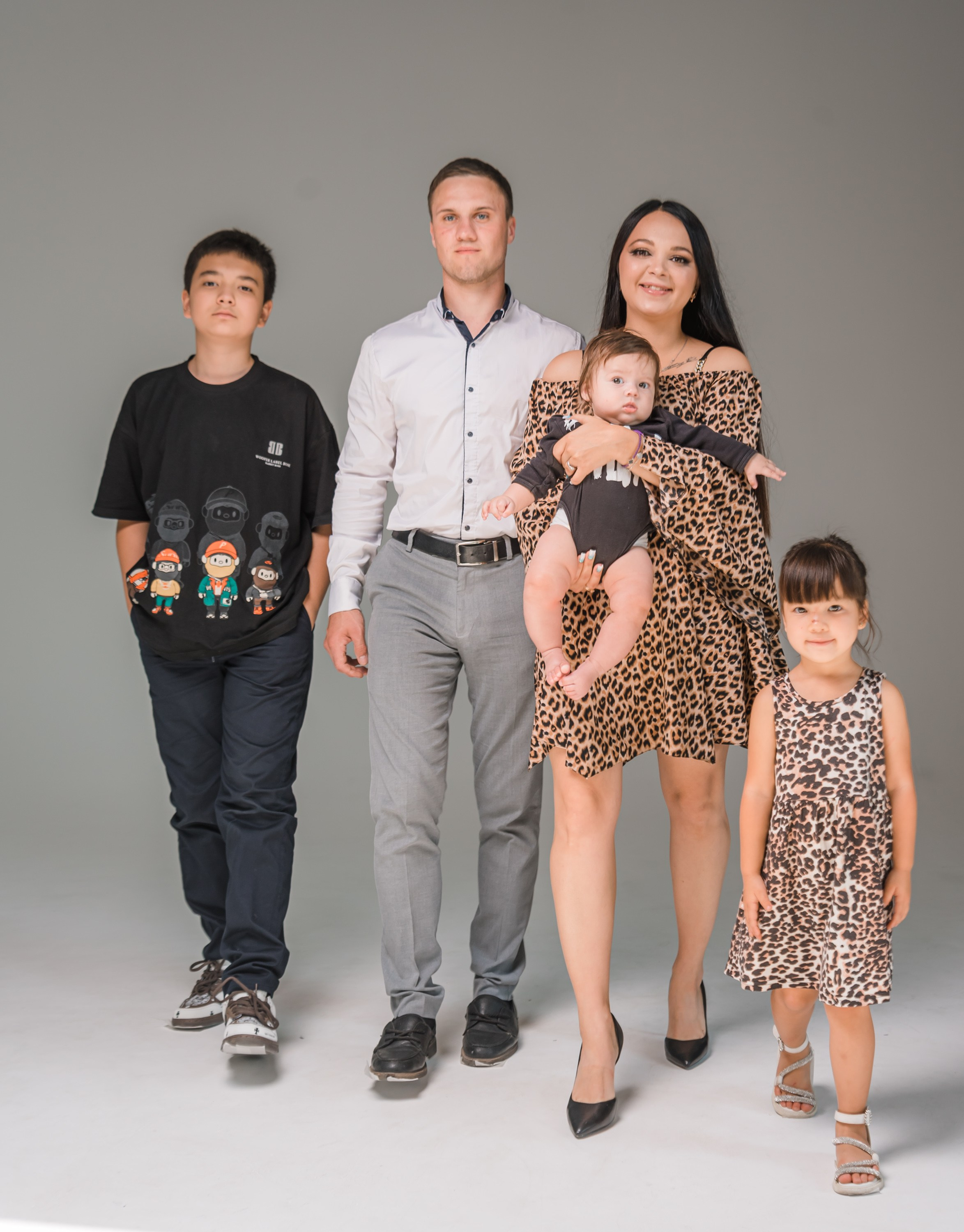 Семейное фото на сером фоне в полный рост.