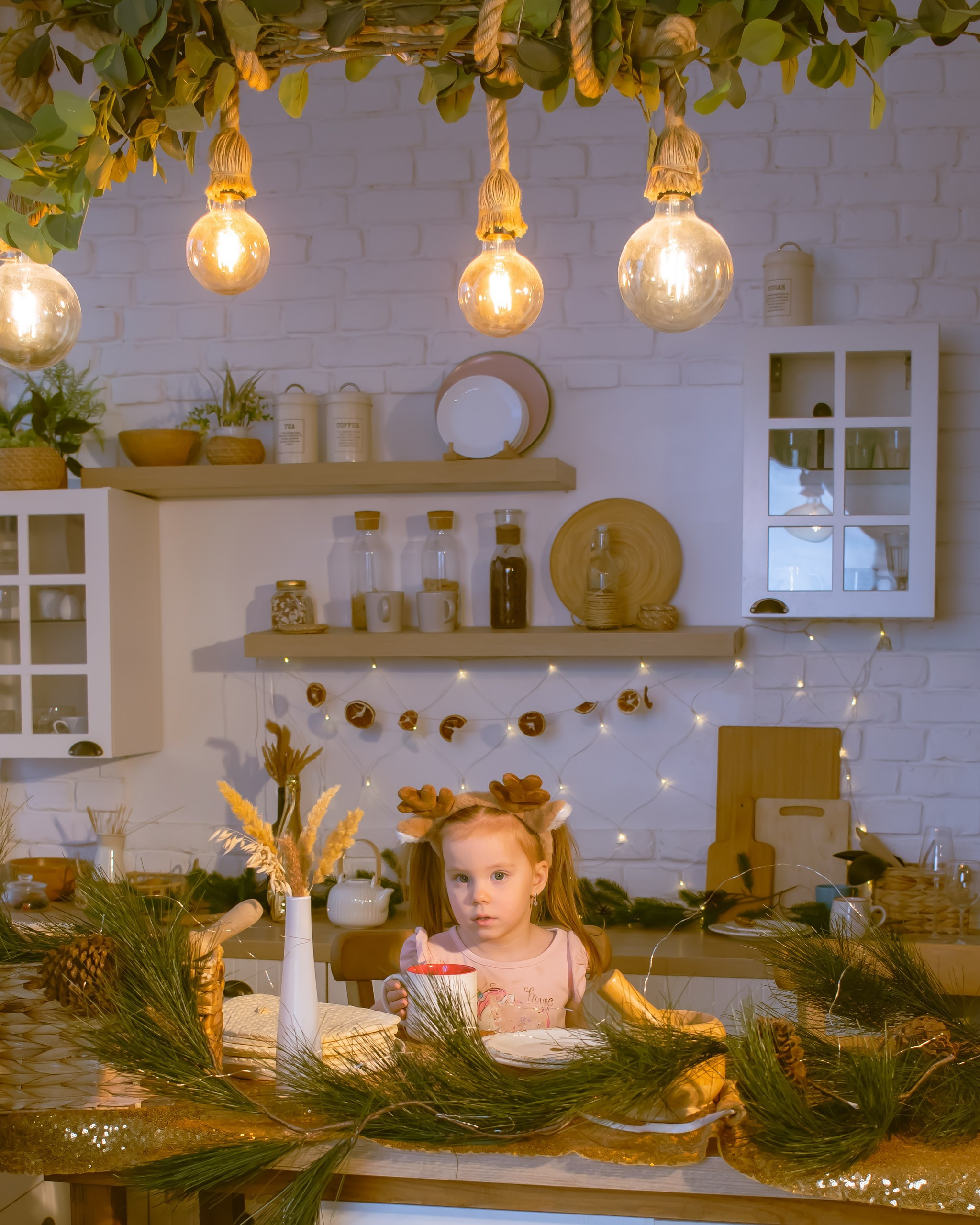 Девочка в рождественском ободке сидит на кухне среди новогоднего декора, зимняя фотосессия, фотограф Карасёва Елена