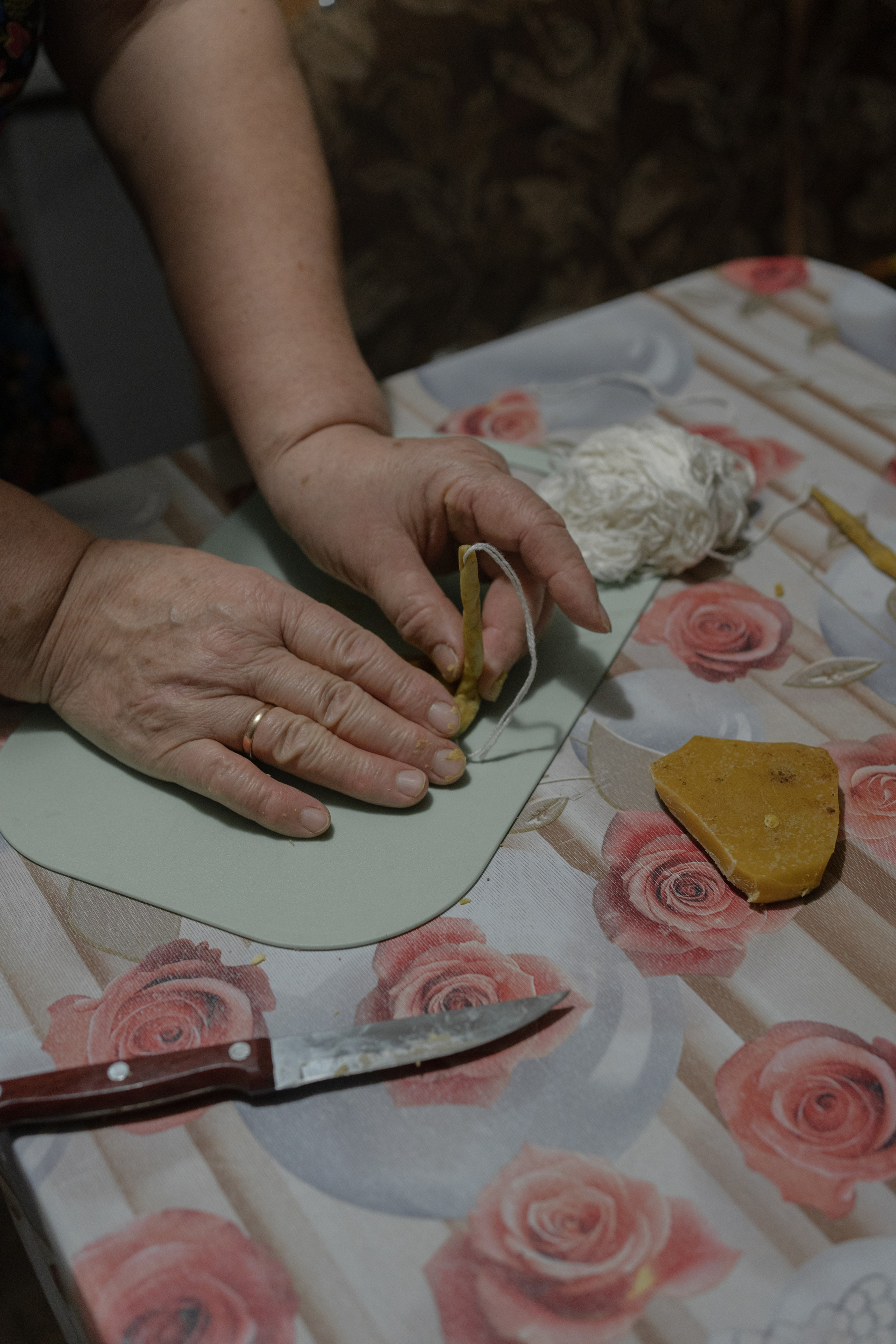 Лидия Викторовна Молянова на кухне своего дома показывает процесс изготовления свечей для чувашского обряда захоронения. В ночь, когда умирает человек, женщины принимаются за приготовление к погребальному обряду. Одна женщина топит воск, а другая рассказывает свечи. Согласно традиционному верованию, смерть человека воспринимается как переход души в загробный мир. Он выступает продолжением земной жизни. Свечами некрещеные чуваши освещают следующий мир покойнику. Село Староганькино, Самарская область, декабрь 2023 год.