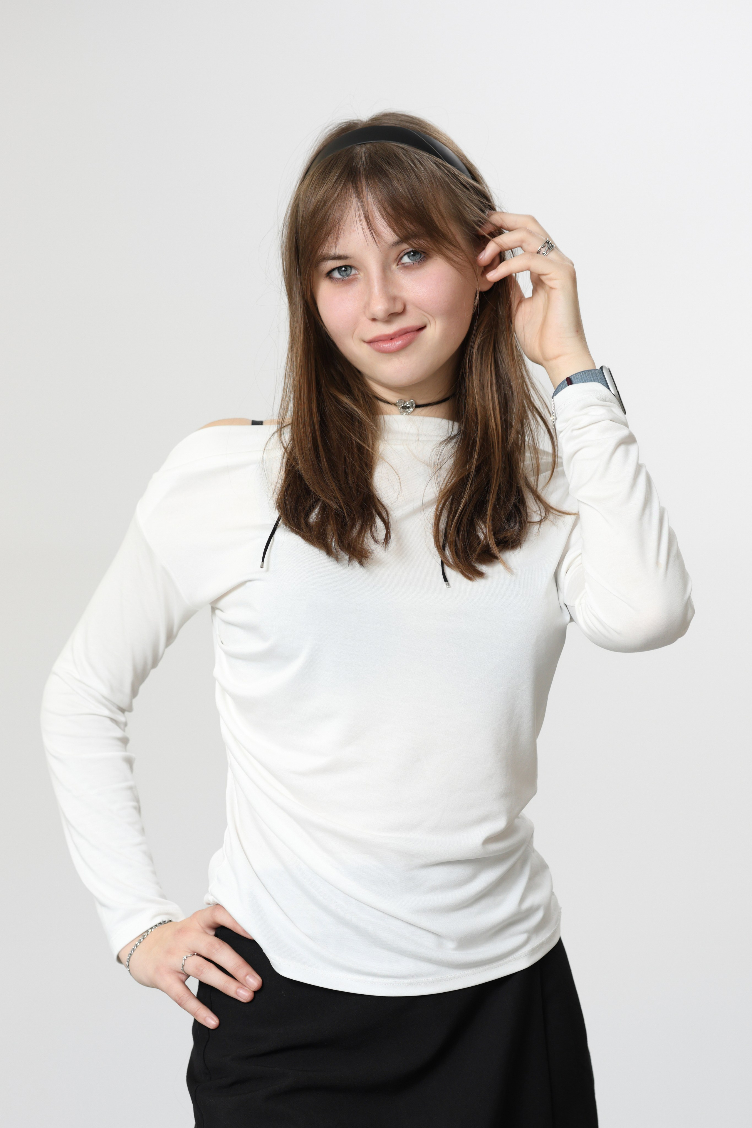 Студийный портрет ученицы в белом лонгсливе на светло-сером фоне.