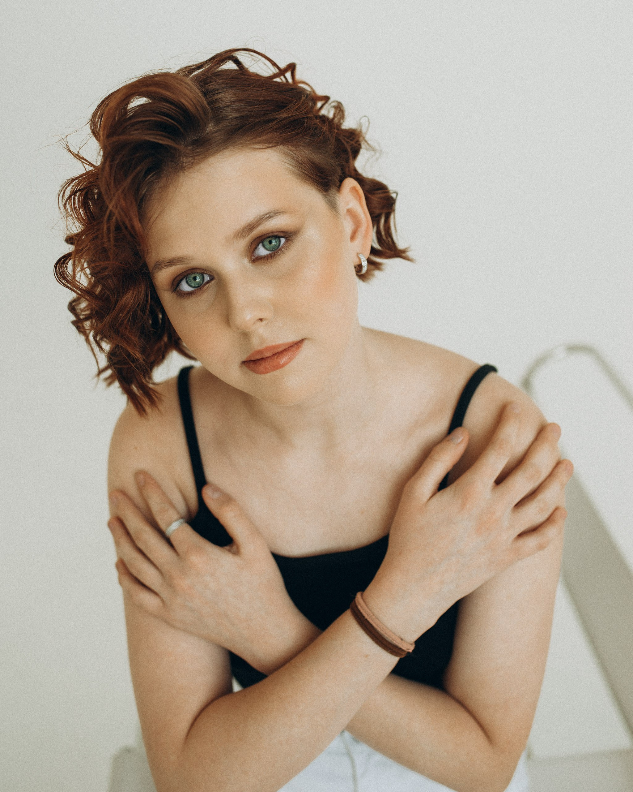 Крупный план девушки сверху: взгляд в объектив, руки скрещены на груди. Акцент на зеленых глазах, рыжих волосах и серебряном кольце. Фотограф Василий Дан