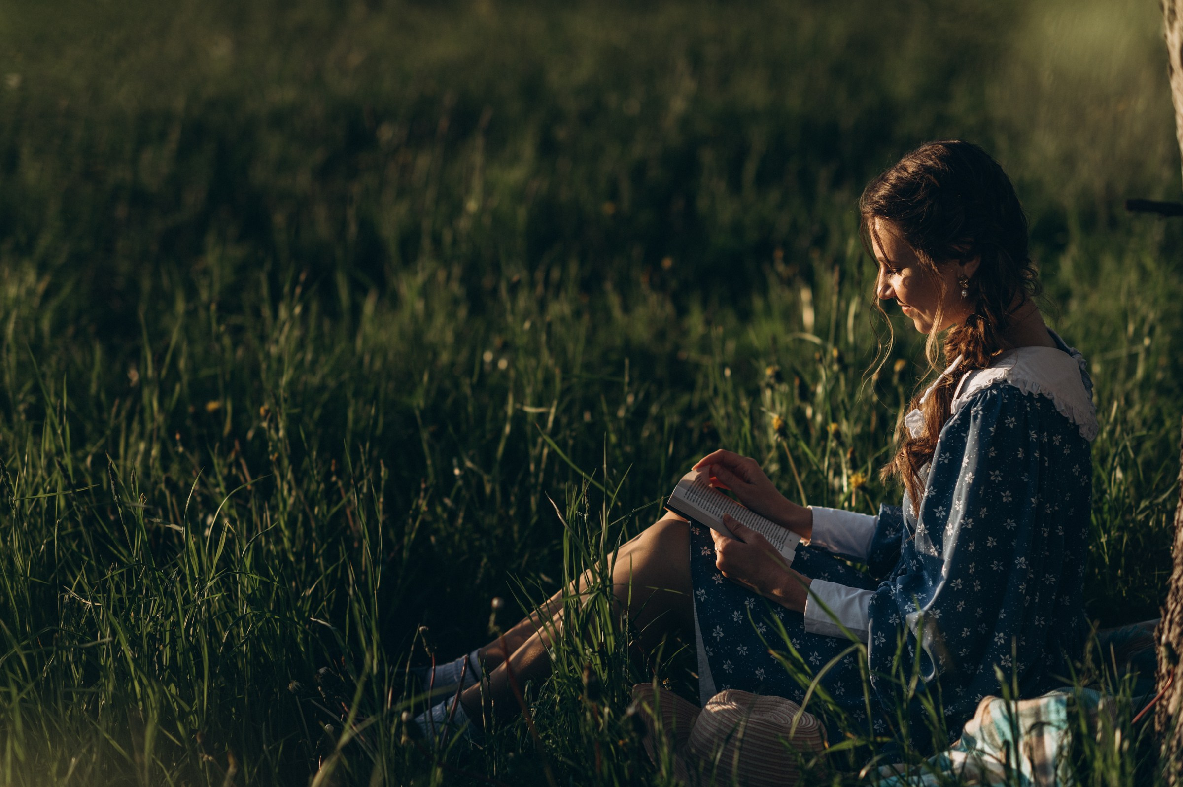 Девушка читает книгу сидя на траве