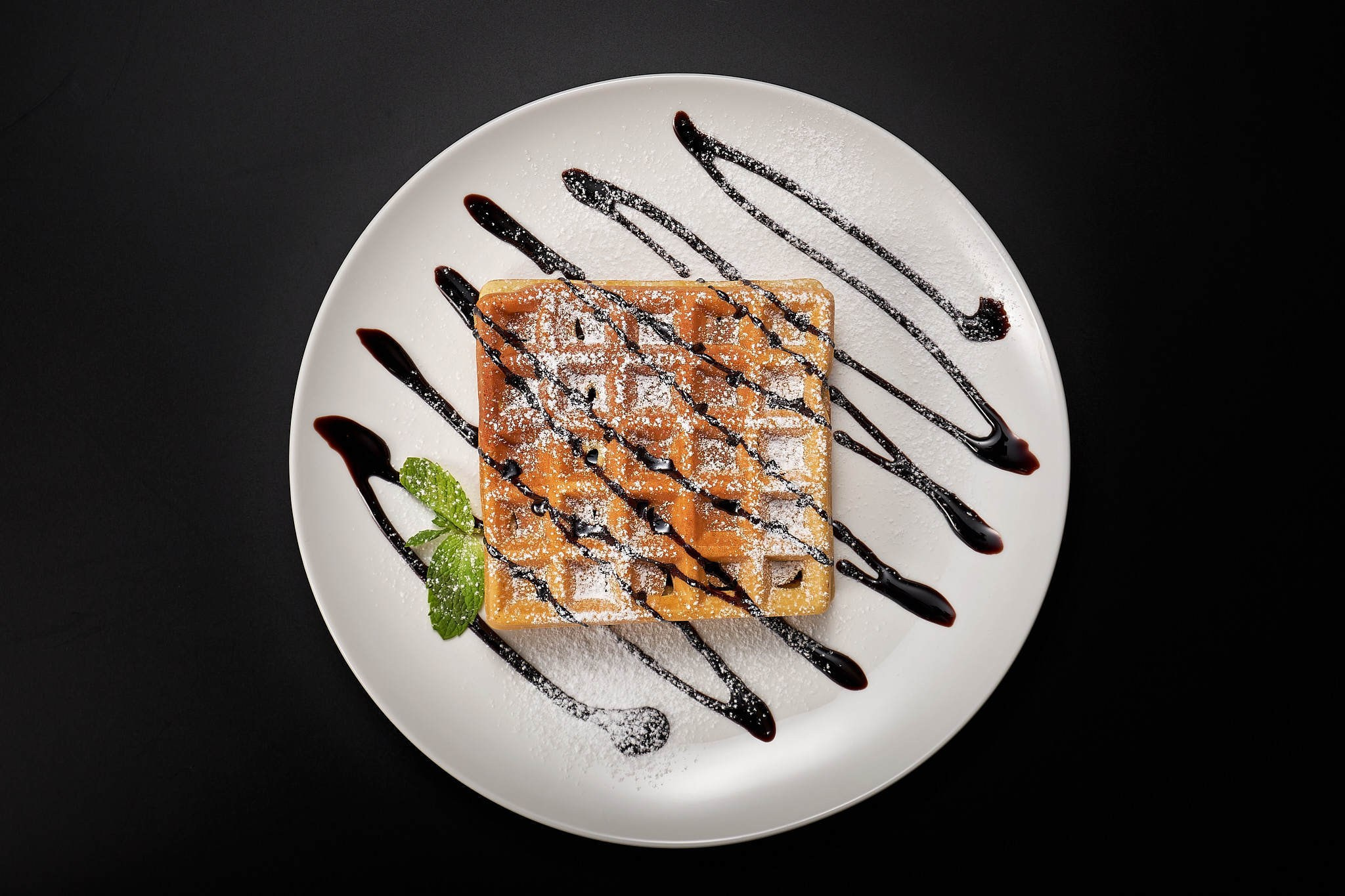 Десерт с шоколадом и мятой на белой тарелке, съёмка сверху