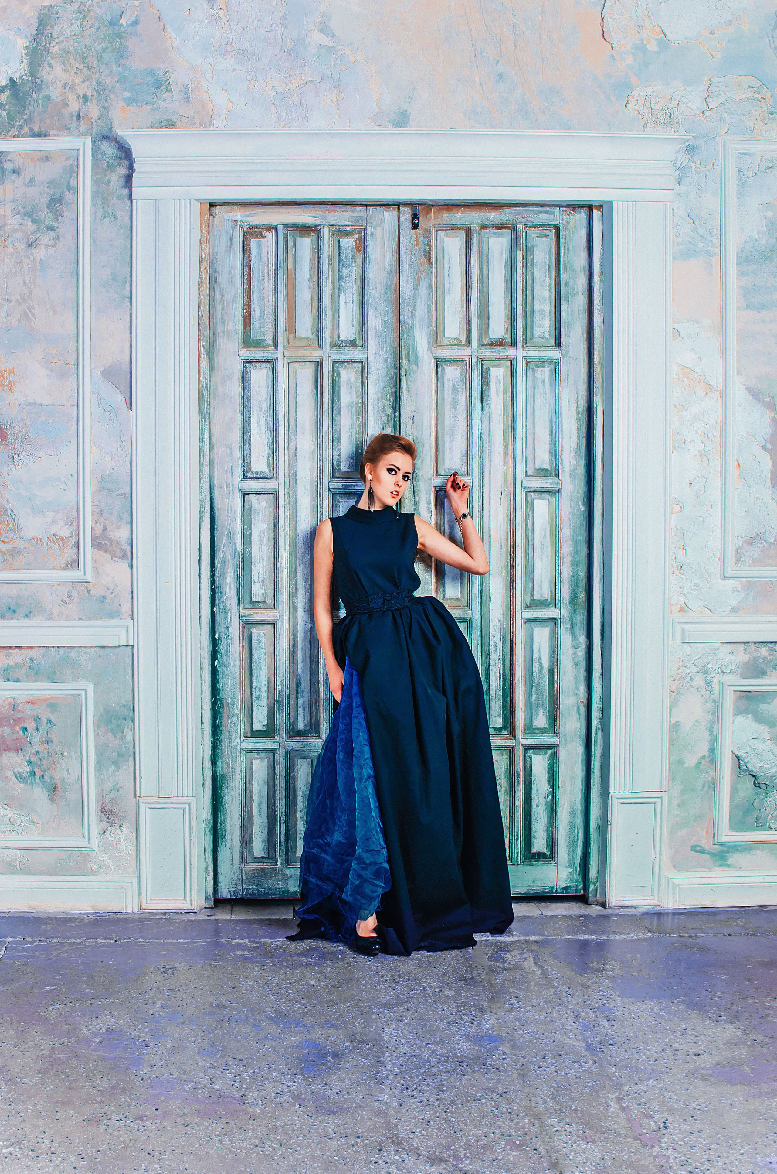 фотосессия девушки в черном платье на фоне большой двери в интерьерной студии спб