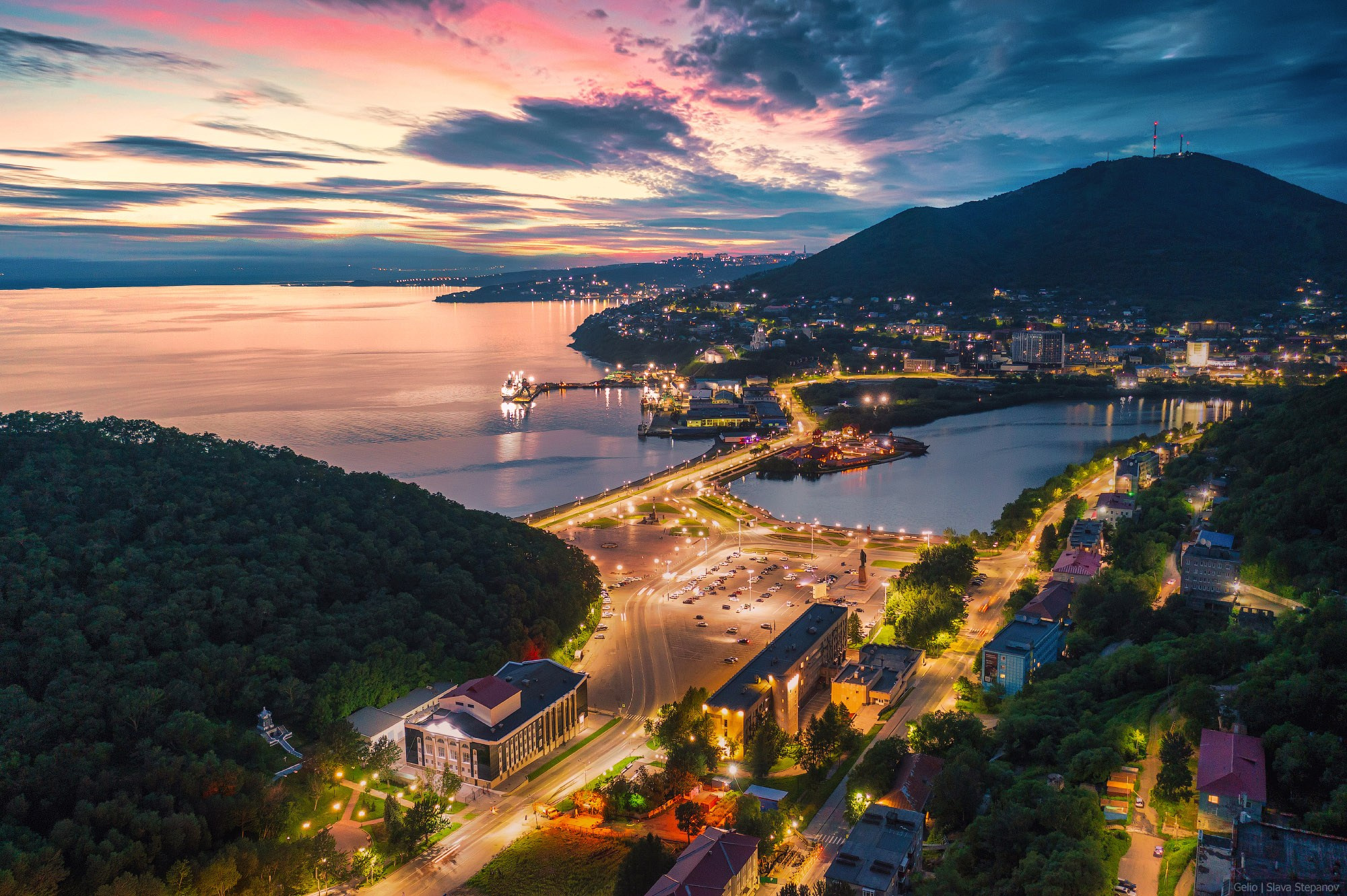 Panoramic view of Petropavlovsk-Kamchatsky and Avacha Bay at sunset. Evening city lights, port infrastructure, and hills from above. Aerial photography, photographer Slava Stepanov.