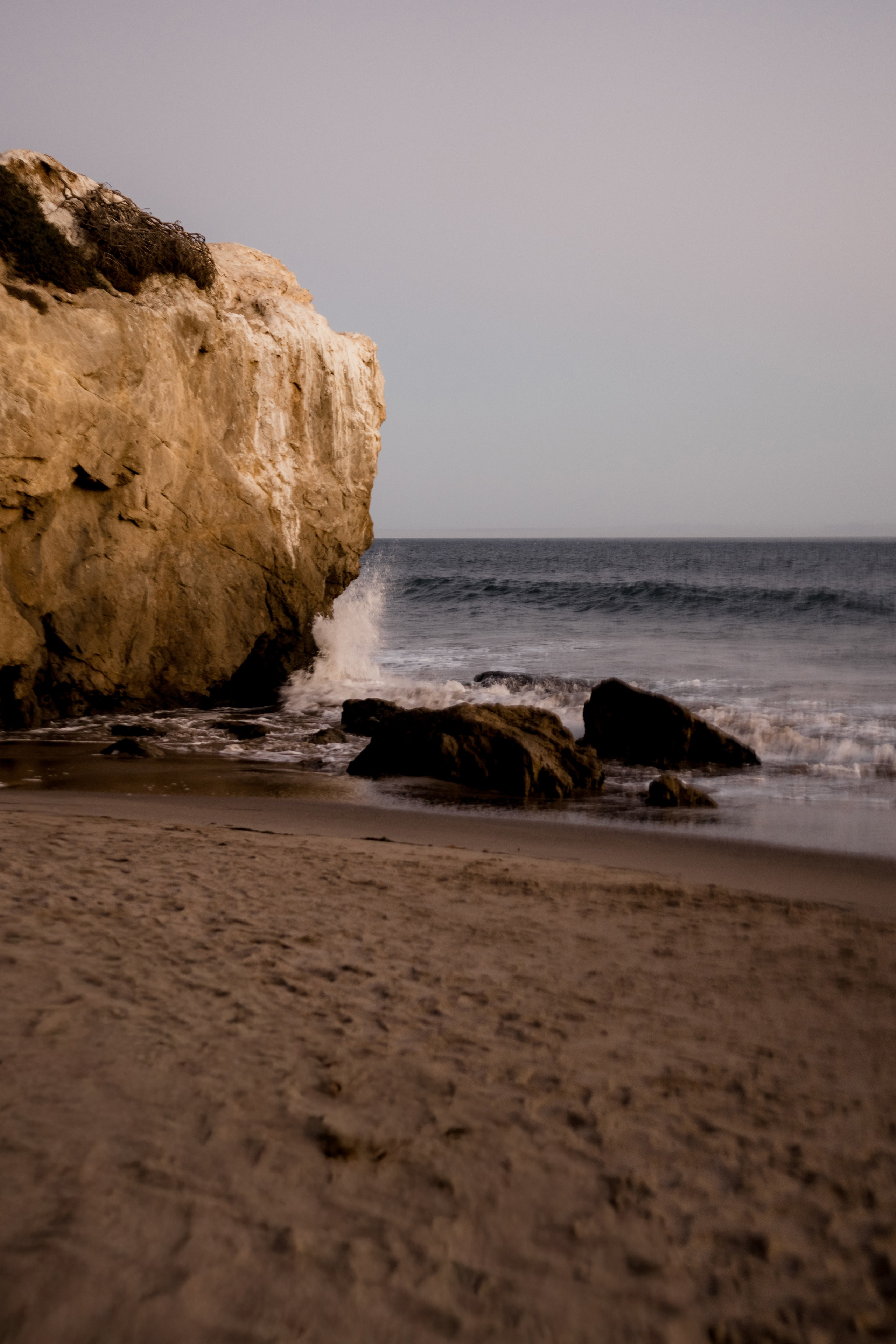 Rocky shoreline during golden hour with waves gently crashing, capturing raw coastal beauty.