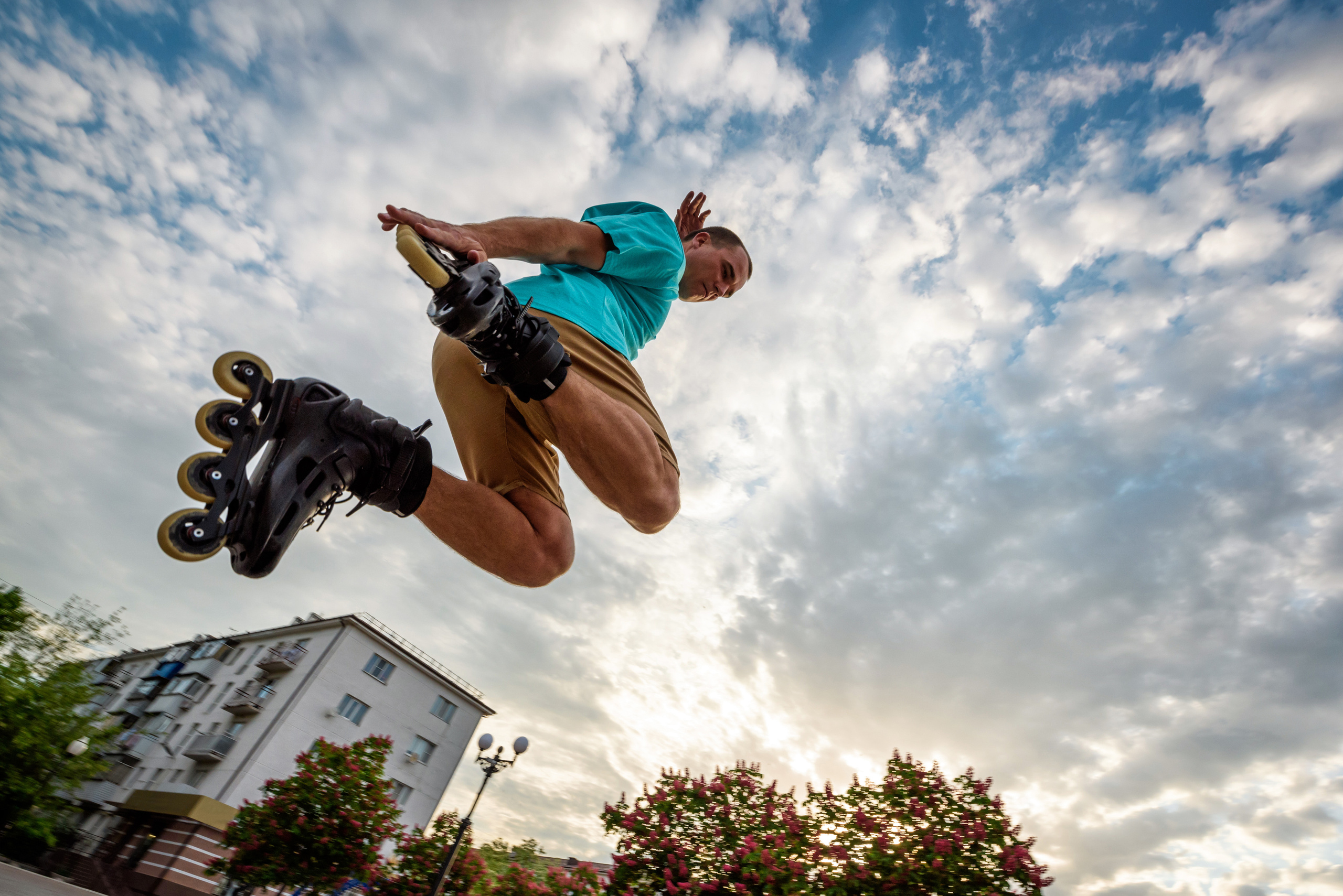 Парень на роликовых коньках, прыжки, фристайл, в небе