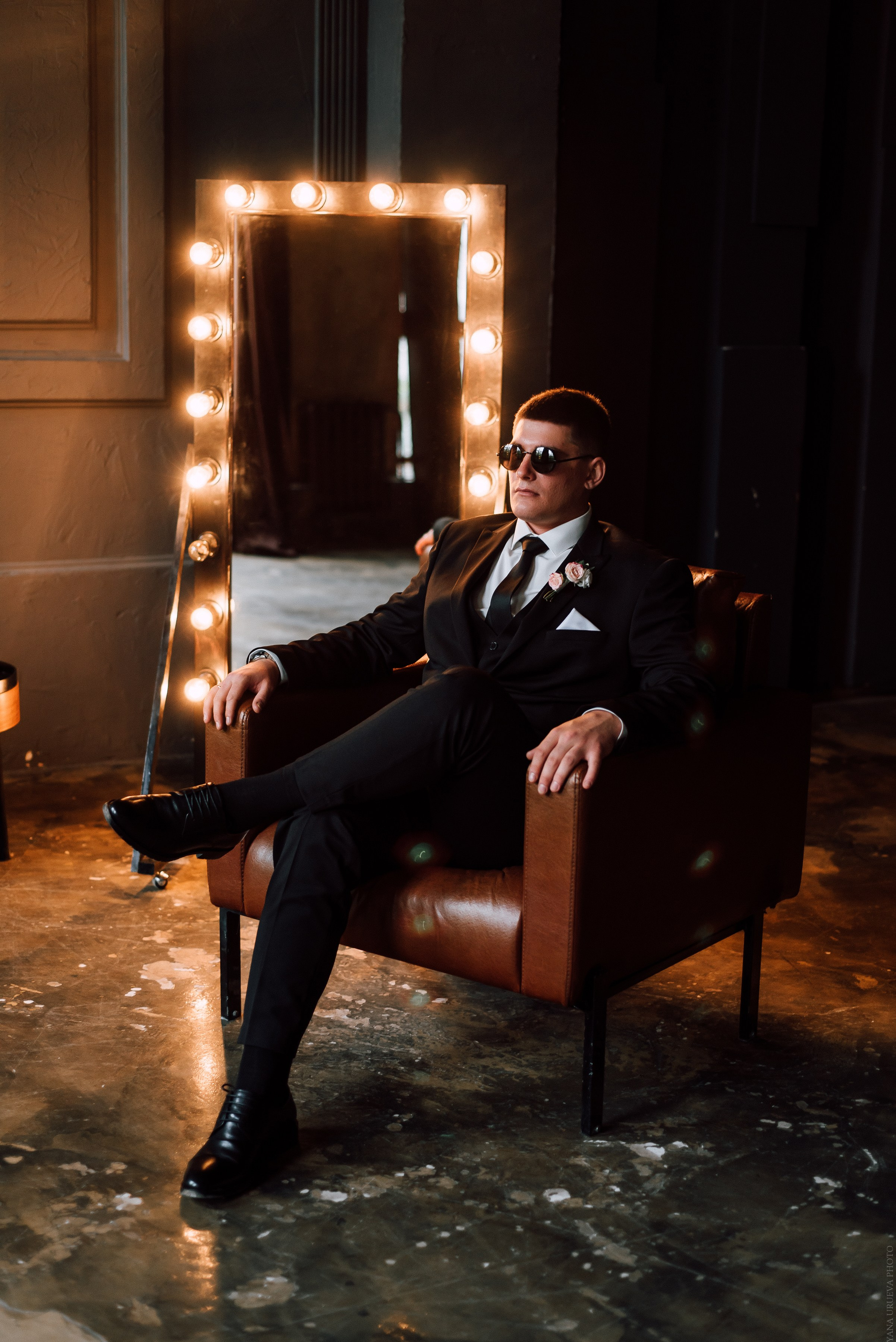 Брутальный молодой человек сидит в кожаном кресле в лофт студии