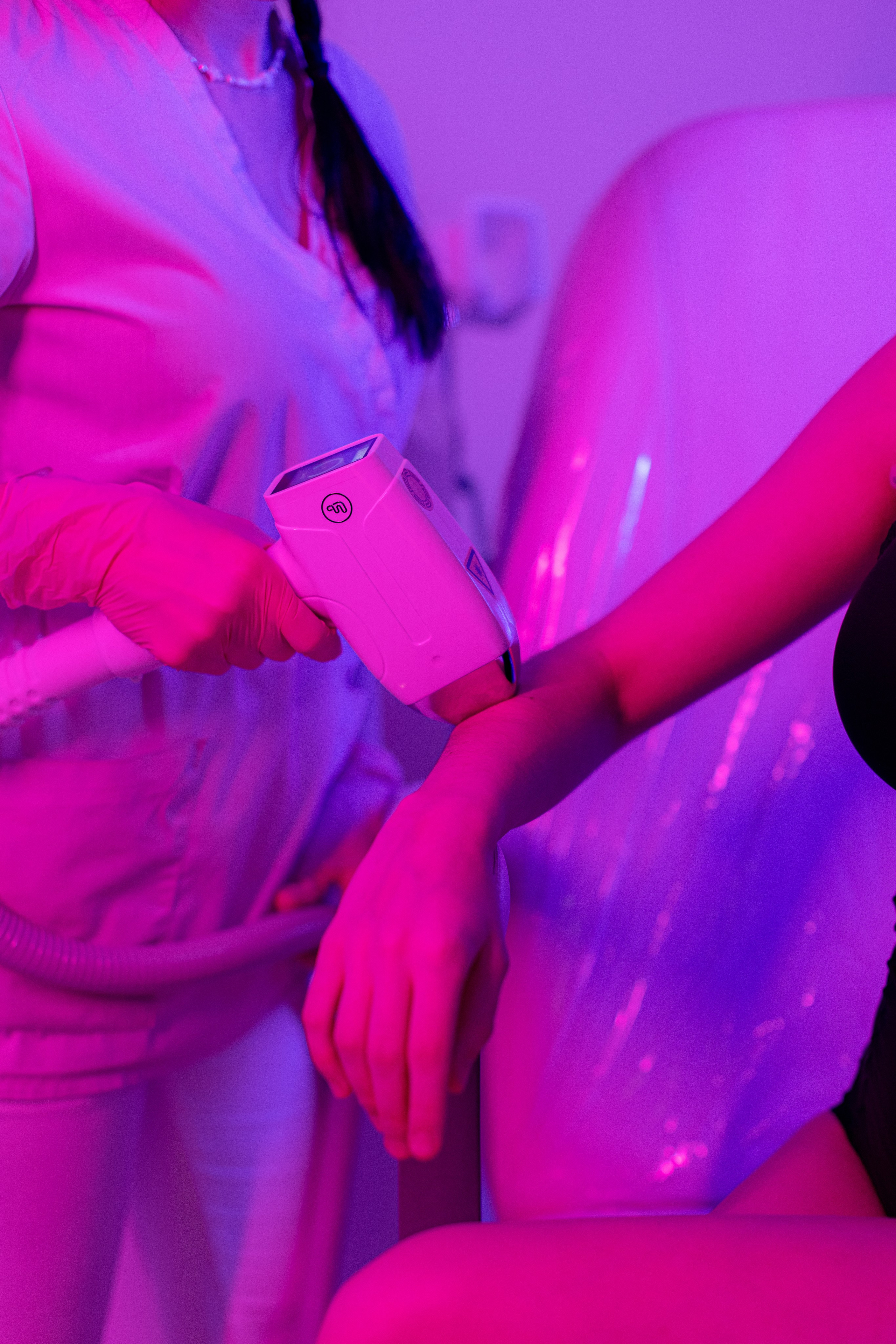 Процедура лазерной эпиляции на руке девушки в неоновом свете