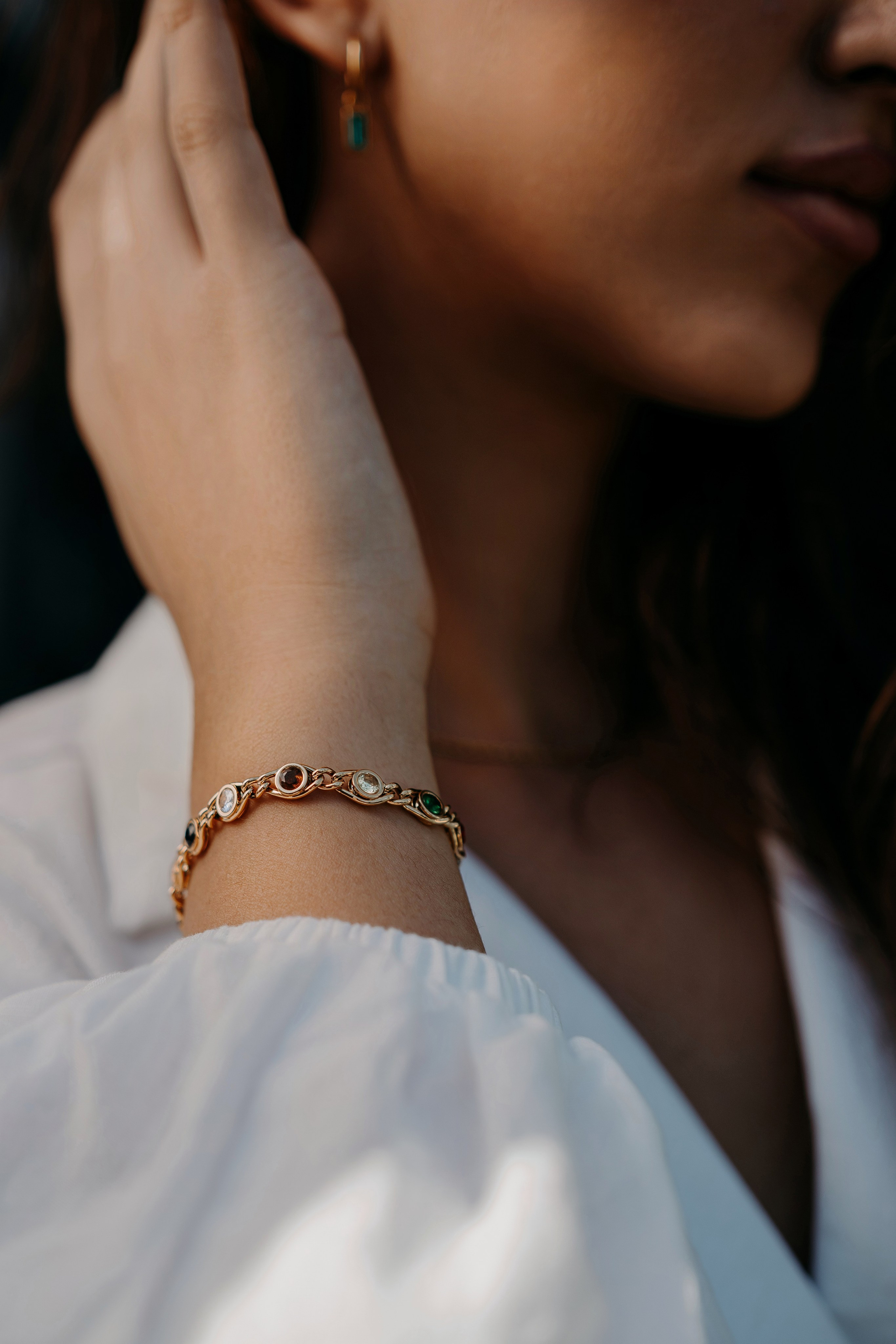 Model showcasing a gold bracelet and earrings in a natural setting, blending elegance and simplicity.