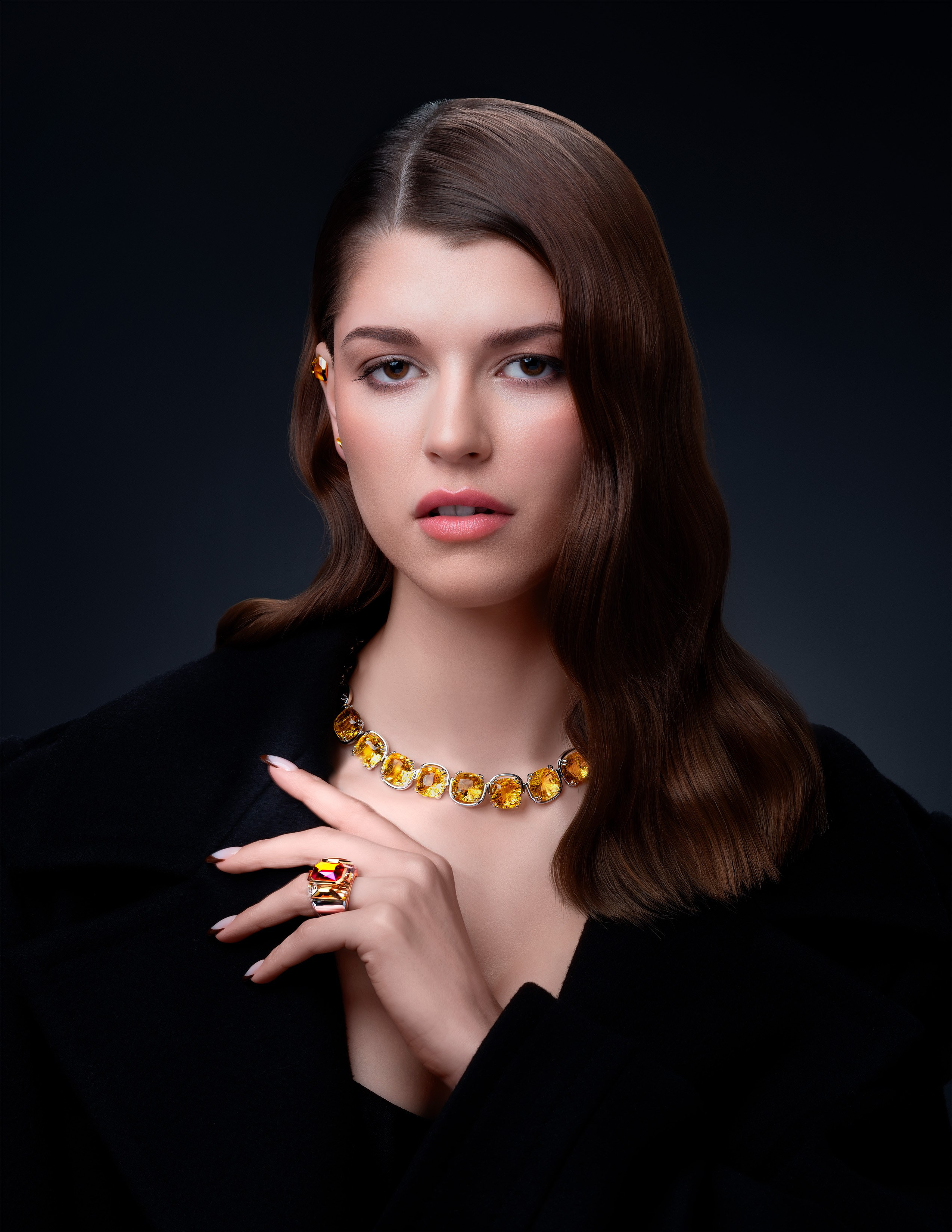 Sophisticated woman showcasing a Swarovski yellow gemstone necklace and matching gold ring – luxury jewelry for timeless elegance.
