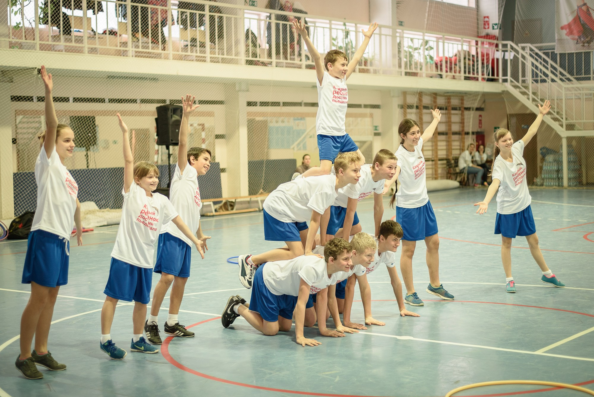Дети в белых футболках и синих шортах показывают спортивный музыкальный номер