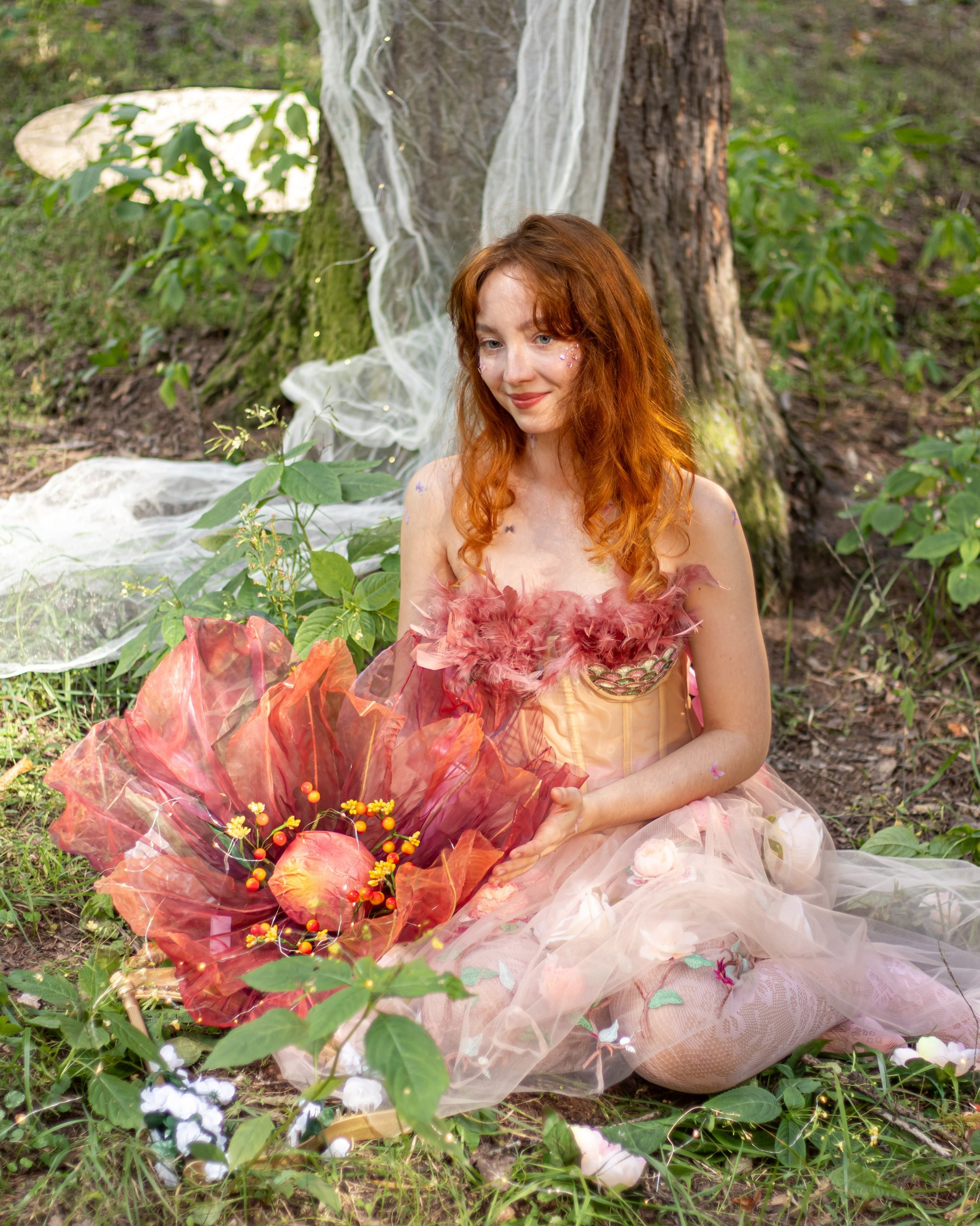 Девушка в розовом платье сидит на поляне с большим цветком — фотосессия в лесу, фотограф