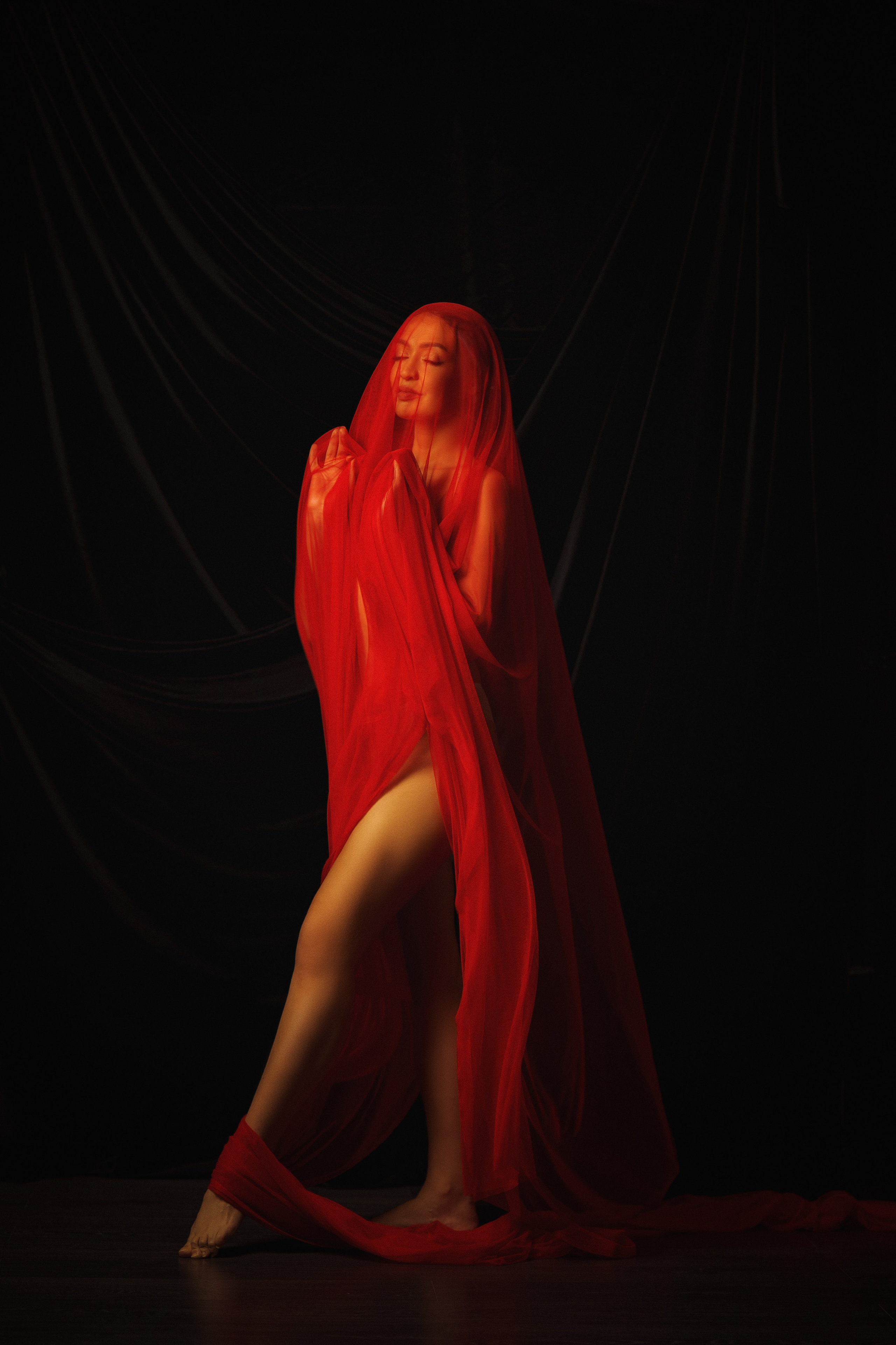 Эстетичная ню съёмка — контраст красной драпировки и тёмного фона