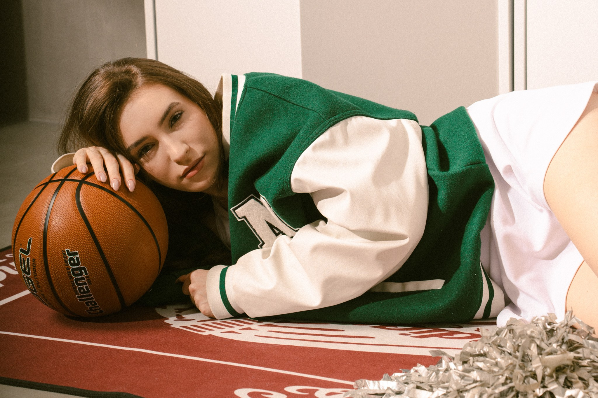 Фотосессия баскетбольной болельщицы с помпонами и мячом в фотостудии в раздевалке