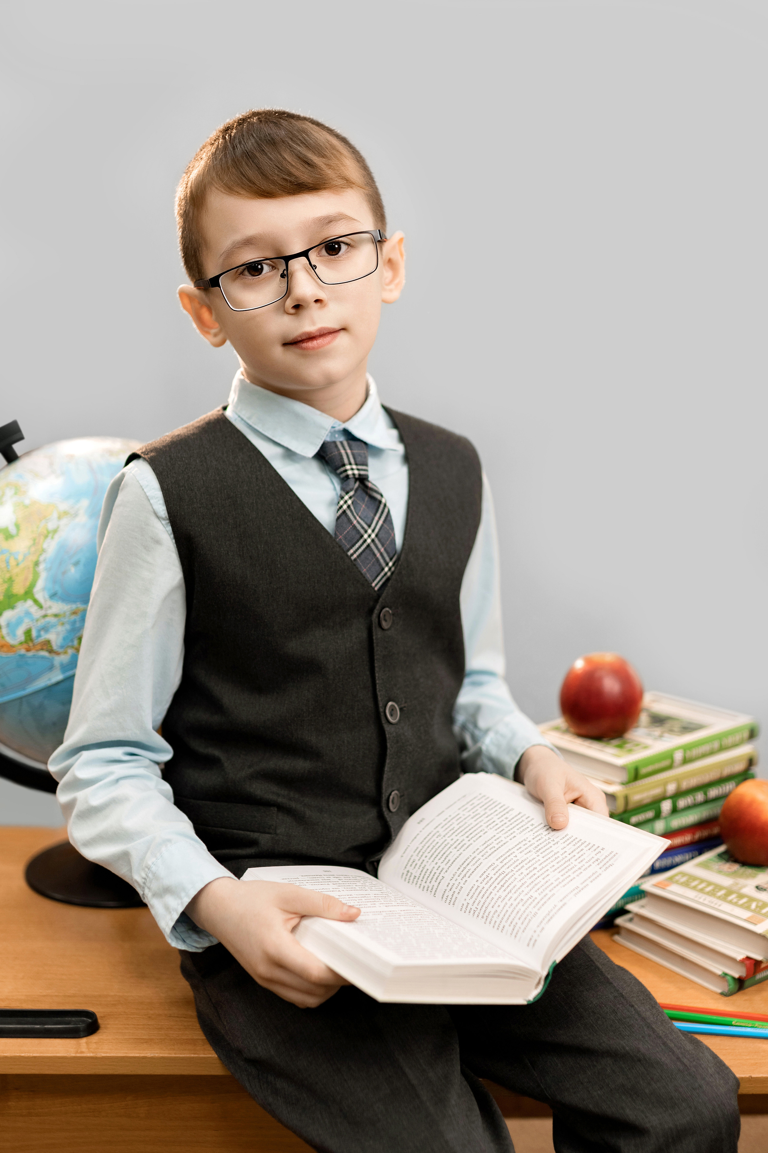 мальчик в школьной форме на парте с книгой и глобусом