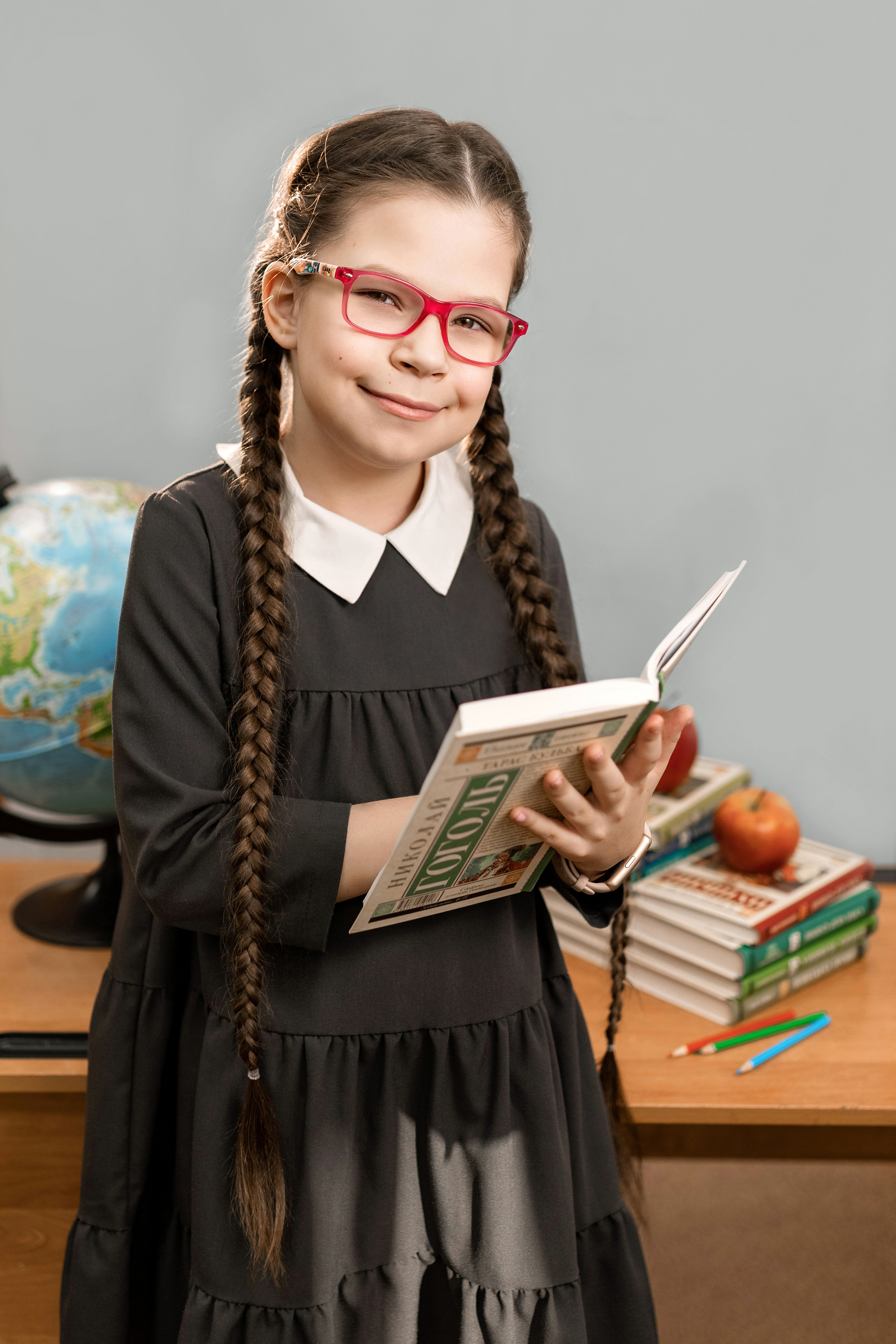 девочка в школе на фотосессии держит книгу