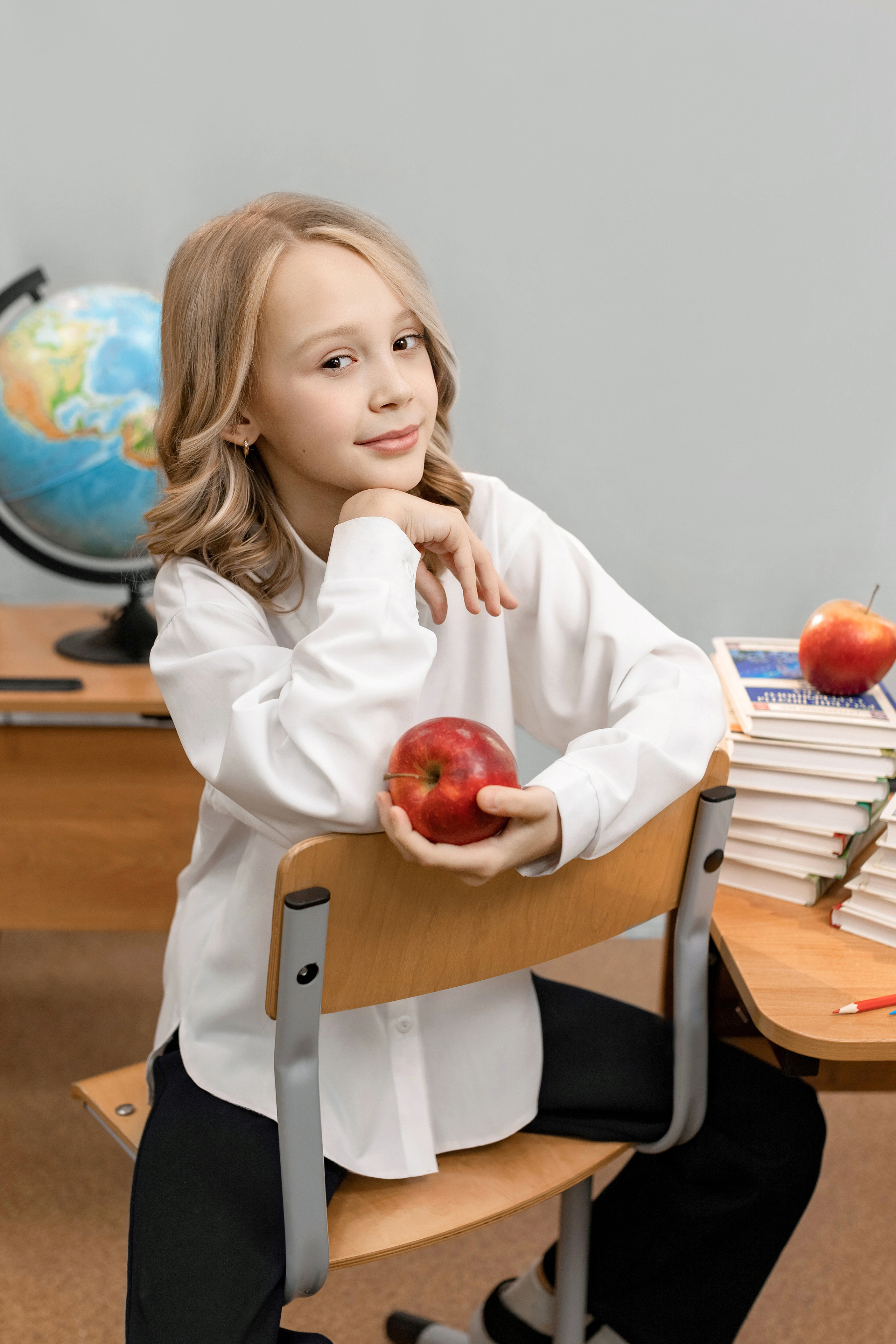 девочка на школьном портрете на стуле с книгой и глобусом