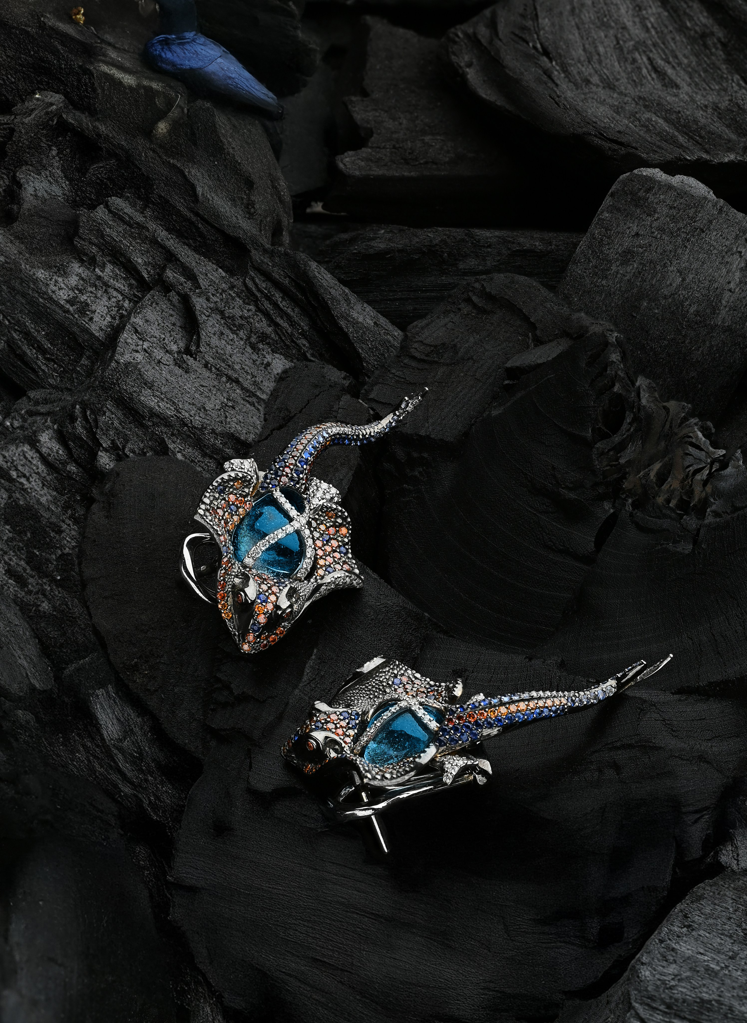 Эксклюзивные серьги в форме рыб с яркими драгоценными камнями на фоне черных текстурированных камней