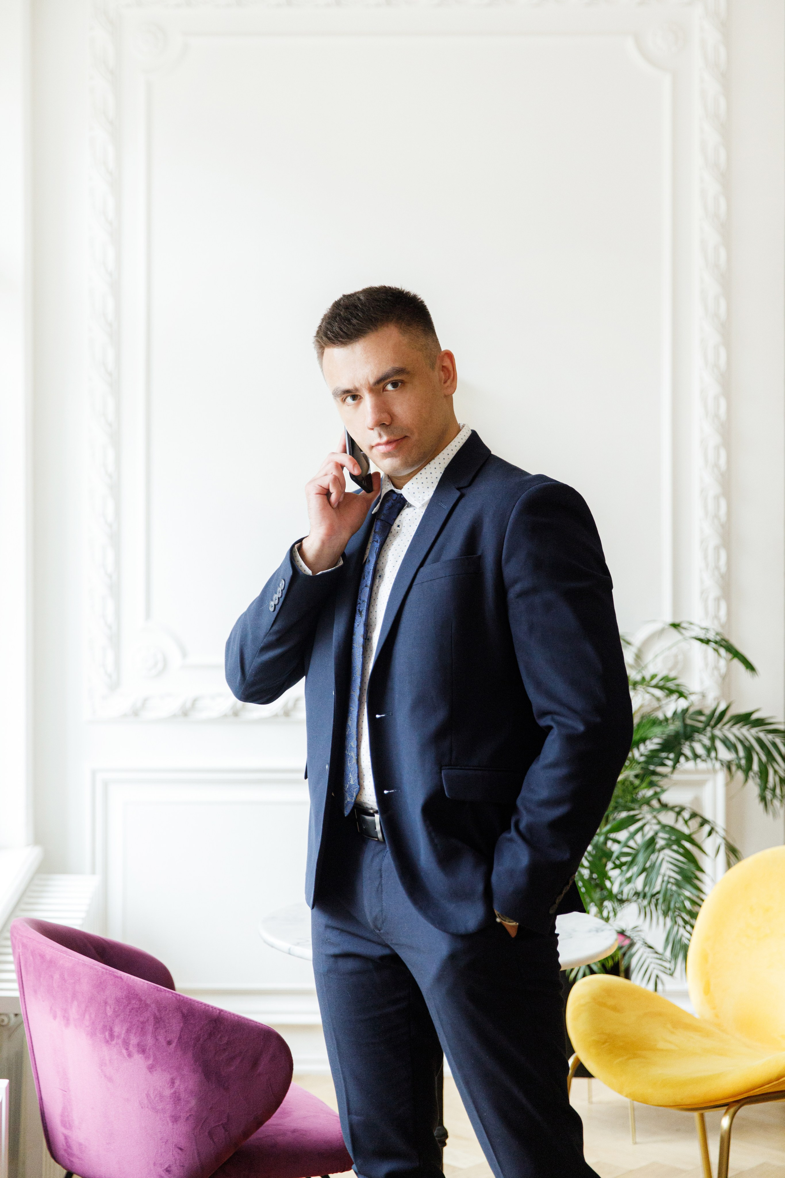 Мужчина в синем костюме с галстуком разговаривает по телефону