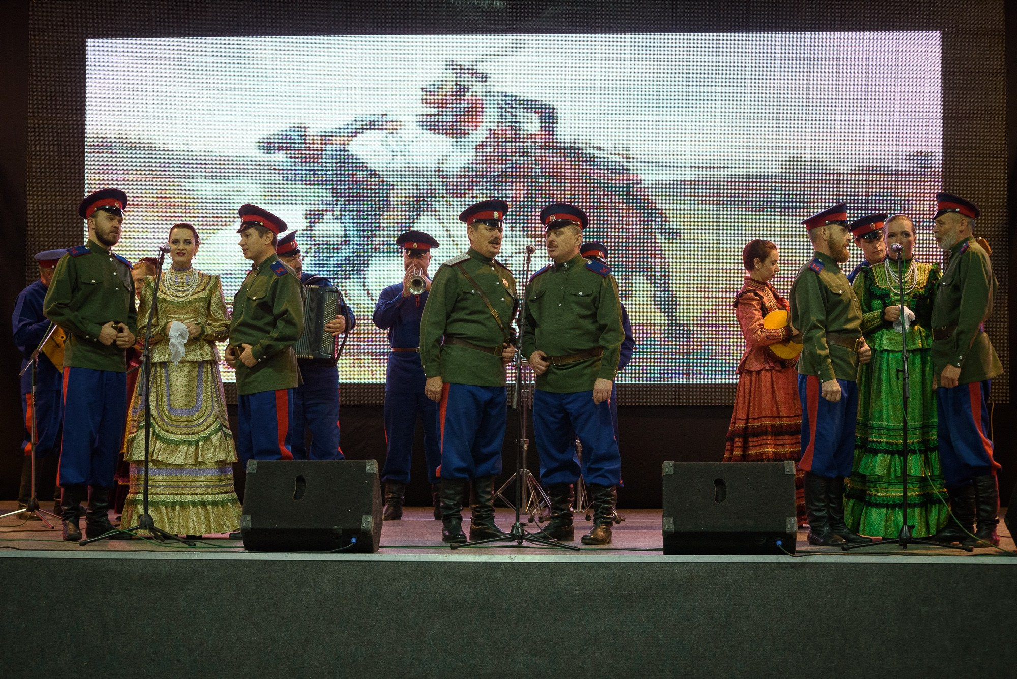 Казачий ансамбль в костюмах на сцене поют песню