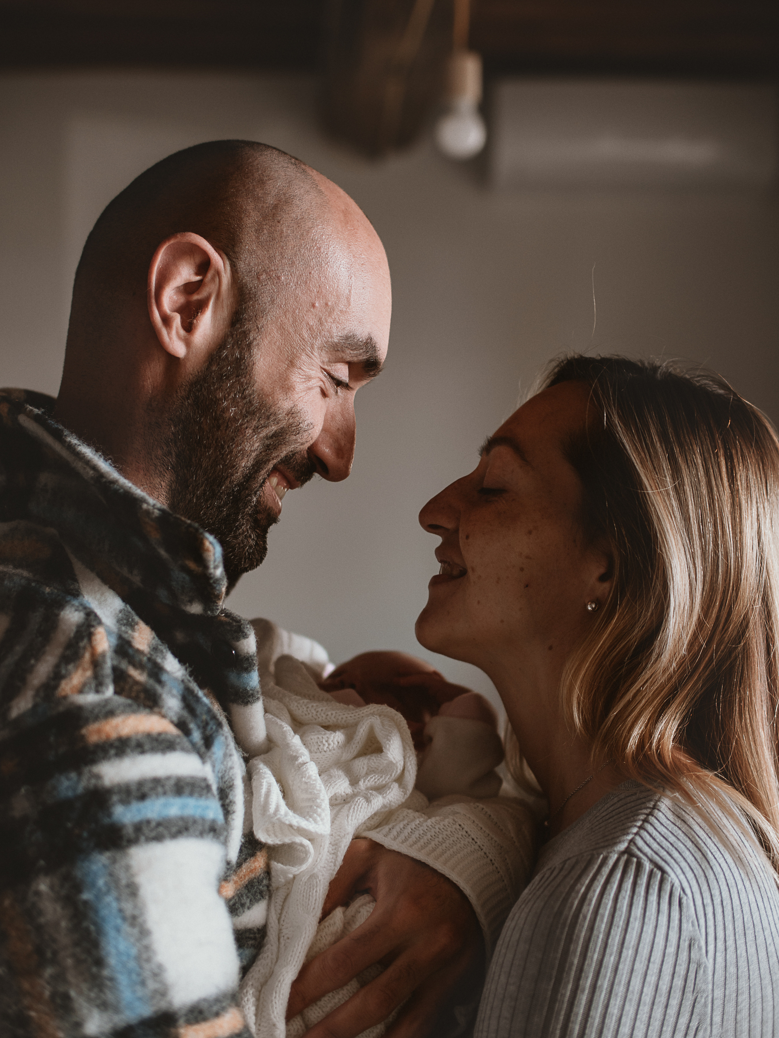 молодые родители смотрят друг на друга с любовью и улыбаются