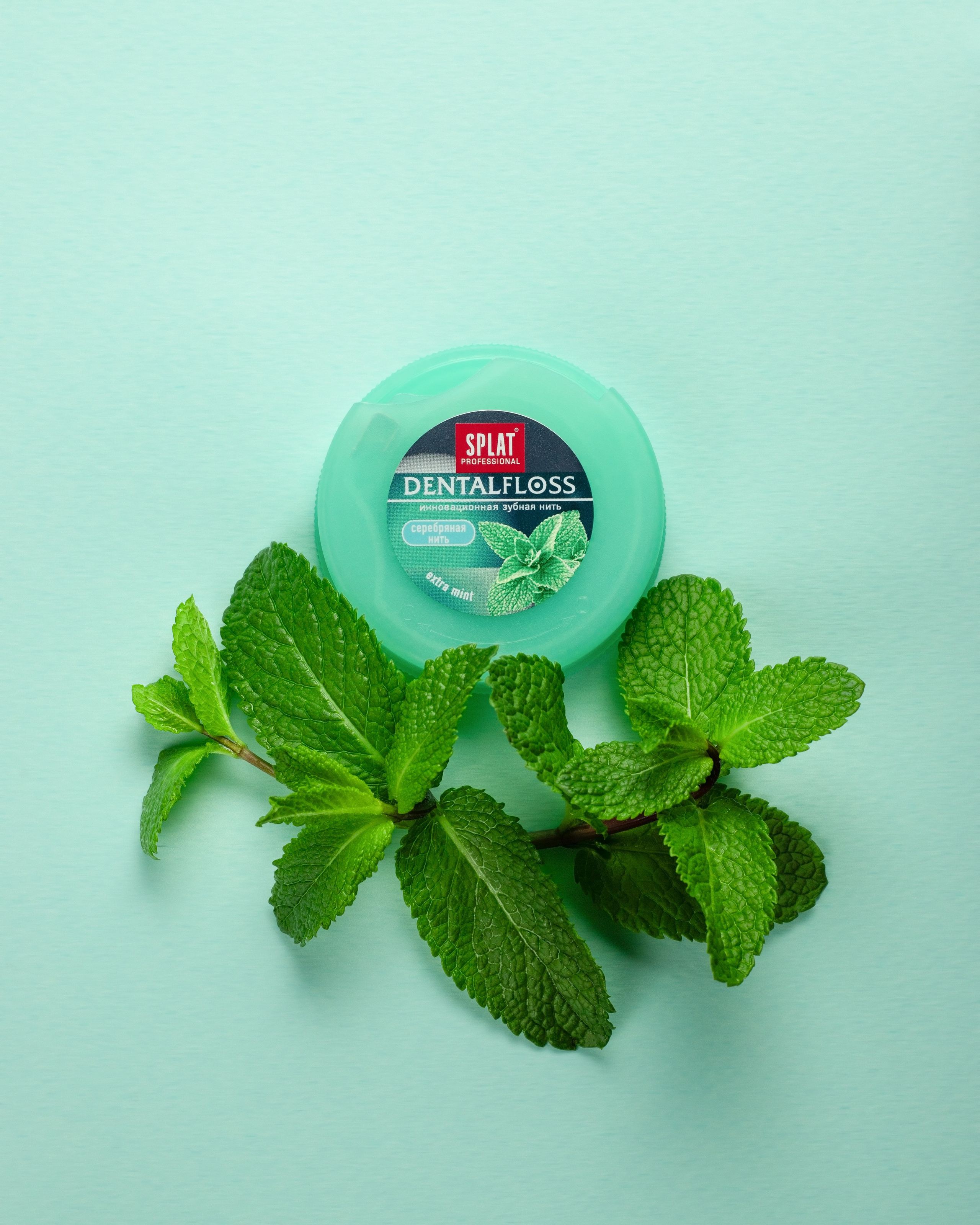 Зубная нить SPLAT с ароматом мяты и свежей мятой на мятном фоне.