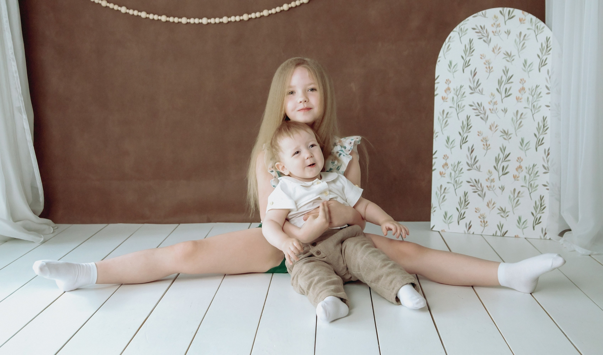 Семейная фотосессия в студии - девочка сидя делает шпагат и мальчик рядом