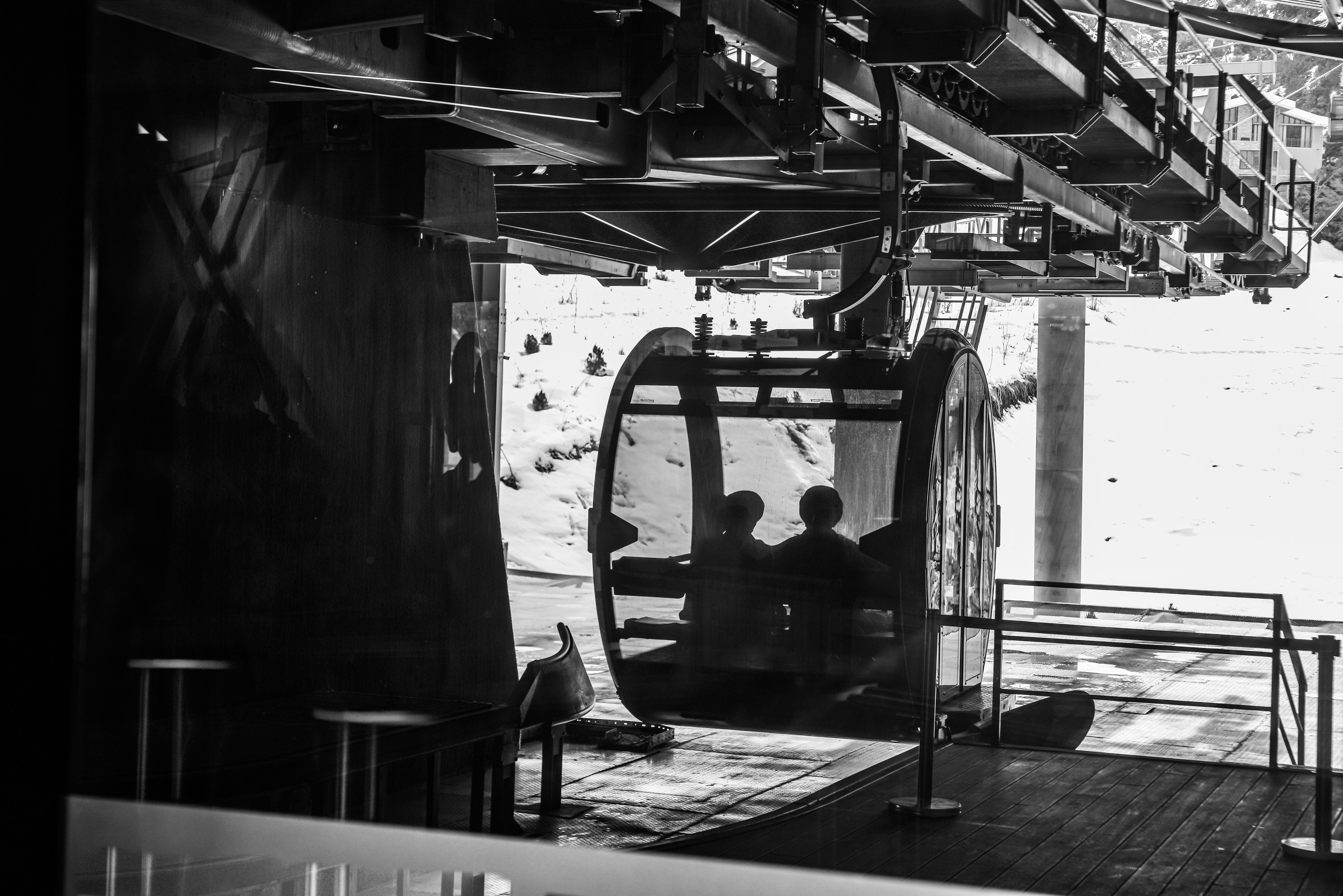 российский мини фотобанк где можно договориться с аавтором и купить фото. на данном фото изображена кабинка горной канатной дороги в чернобелых цветах. в кабинке сидят твое - силуэты