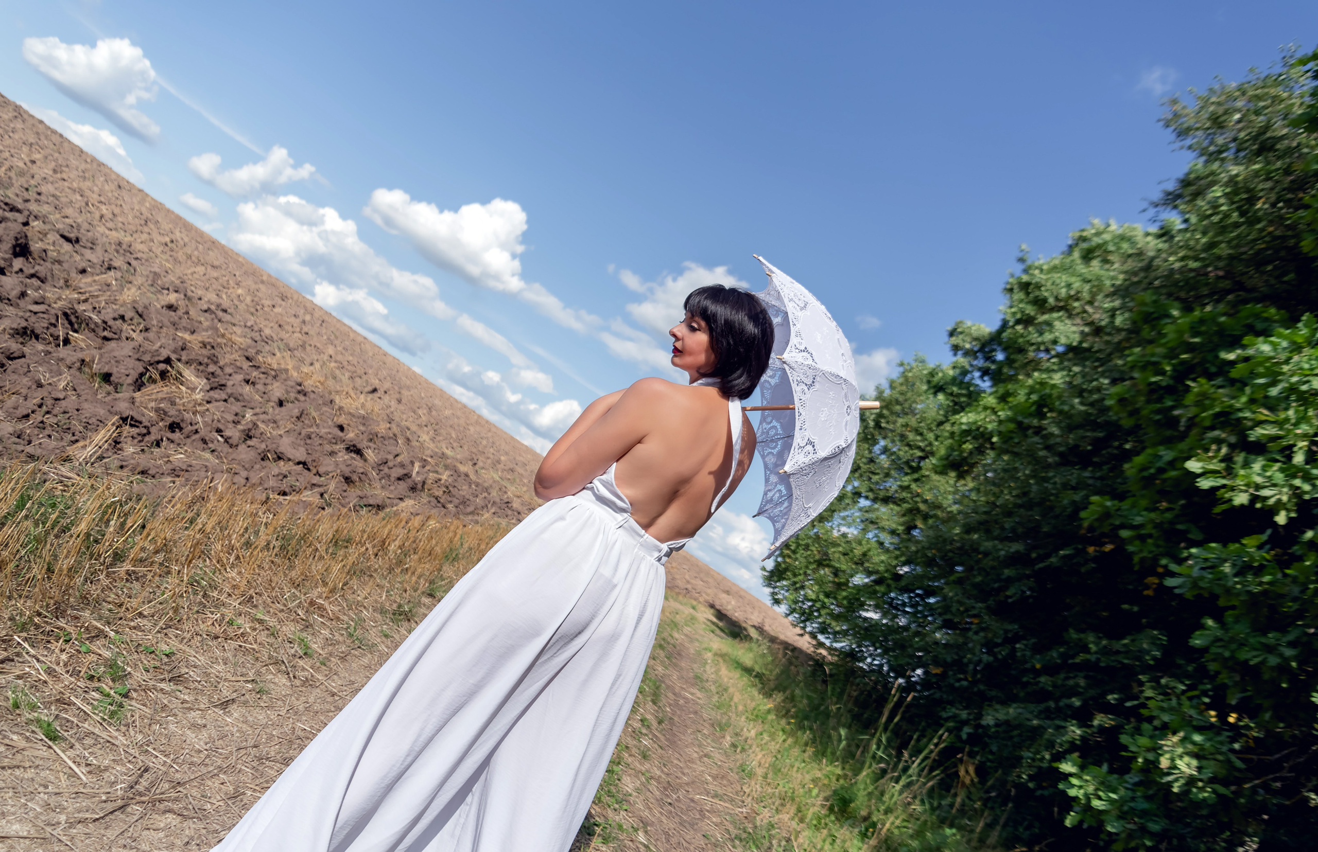 На фото девушка в поле с зонтом.