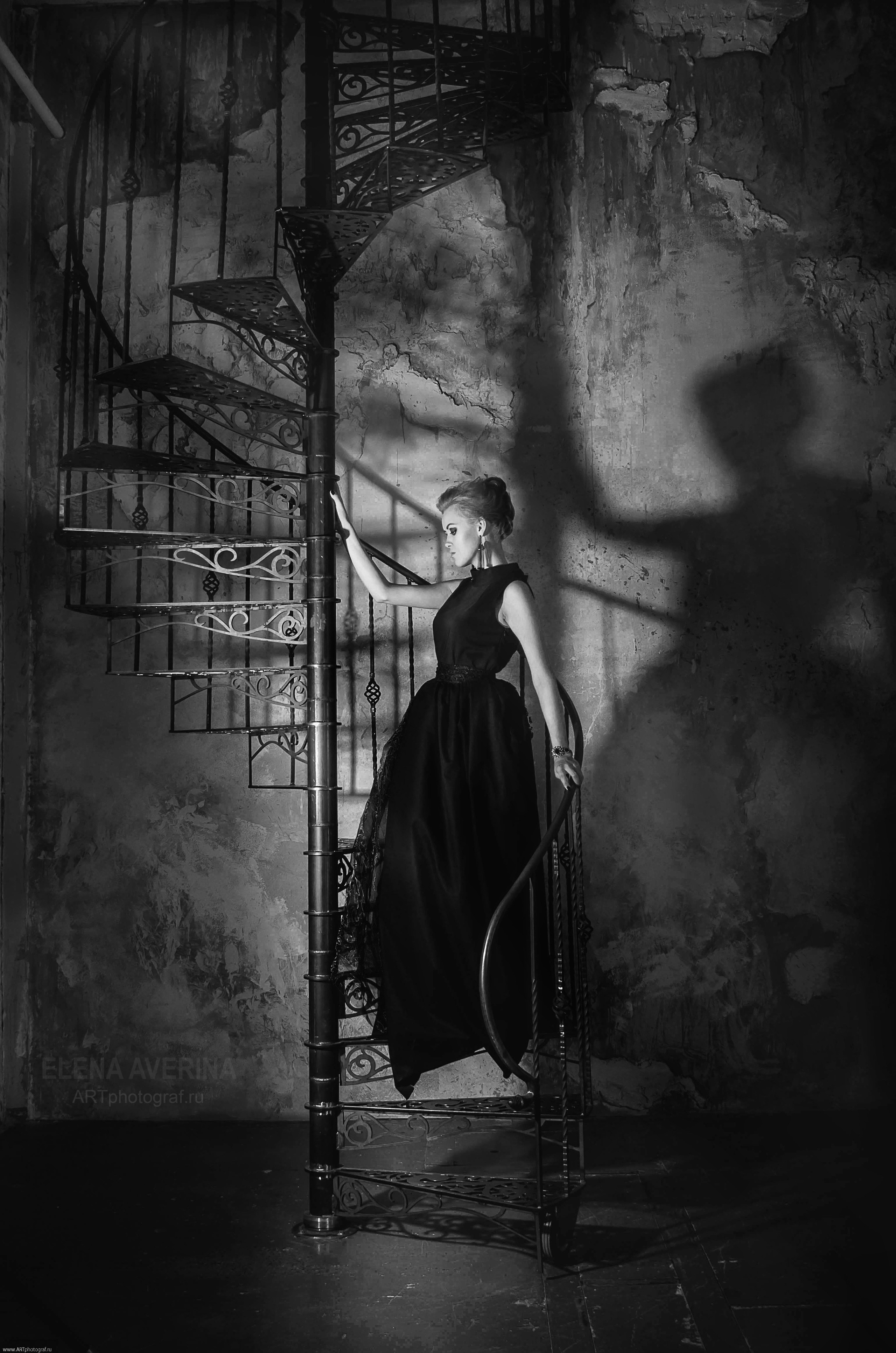 красивая черно-белая фотография девушки в черном платье на винтовой лестнице