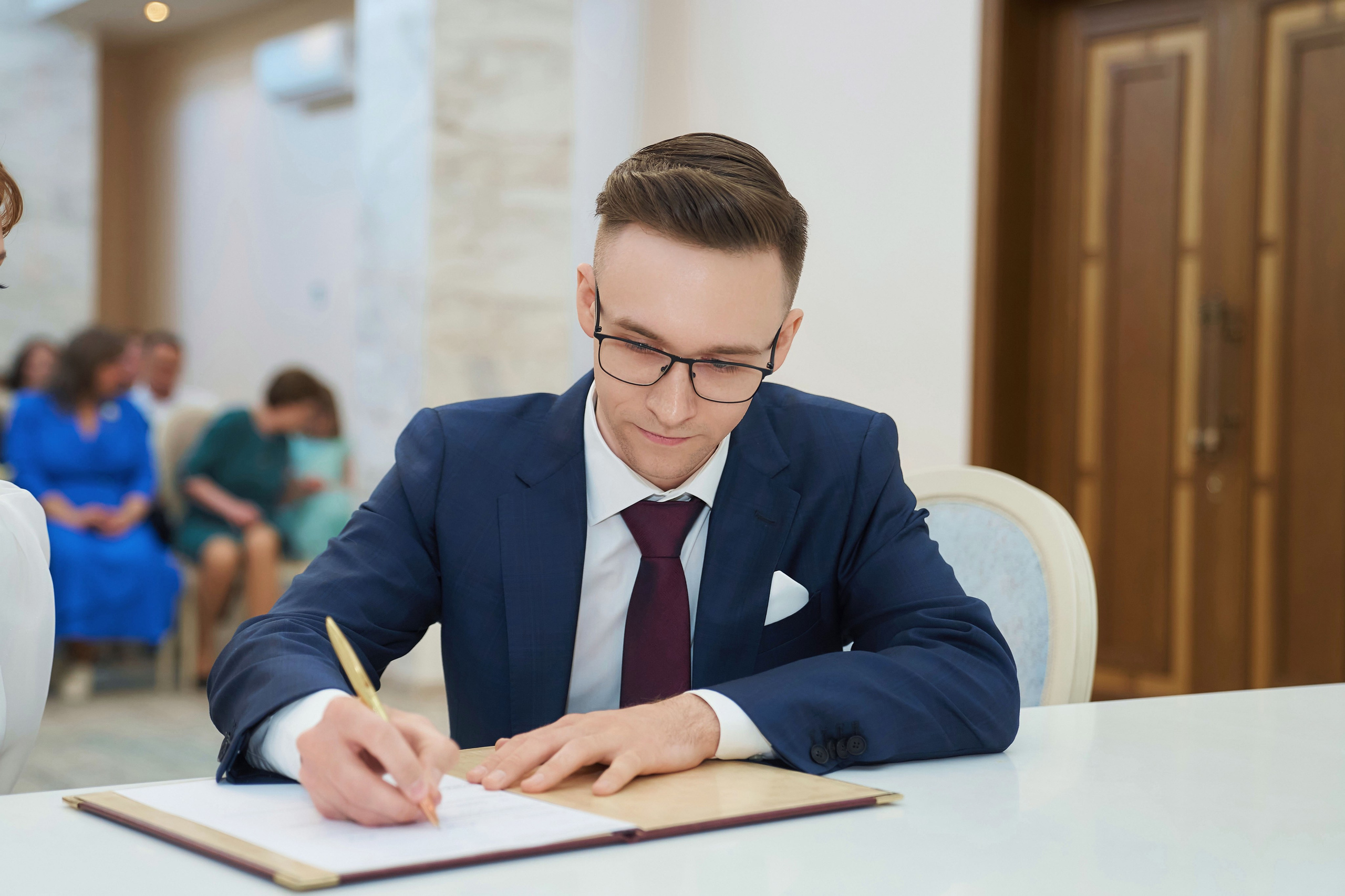 жених ставит подпись во время регистрации брака