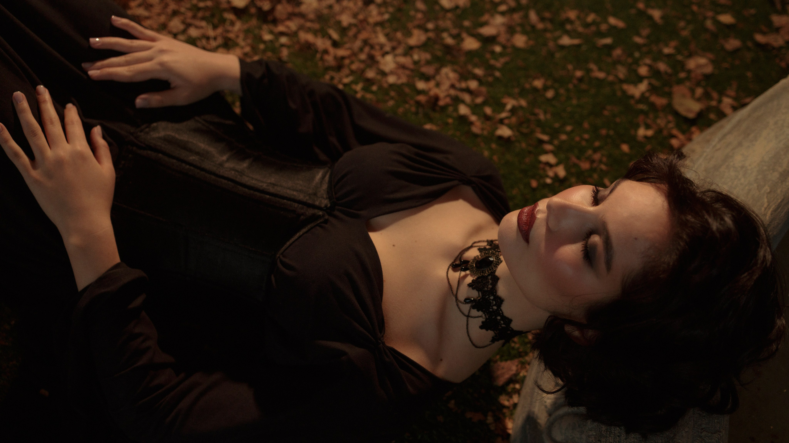 Девушка лежит головой на краю фонтана, глаза закрыты, руки сложены на животе