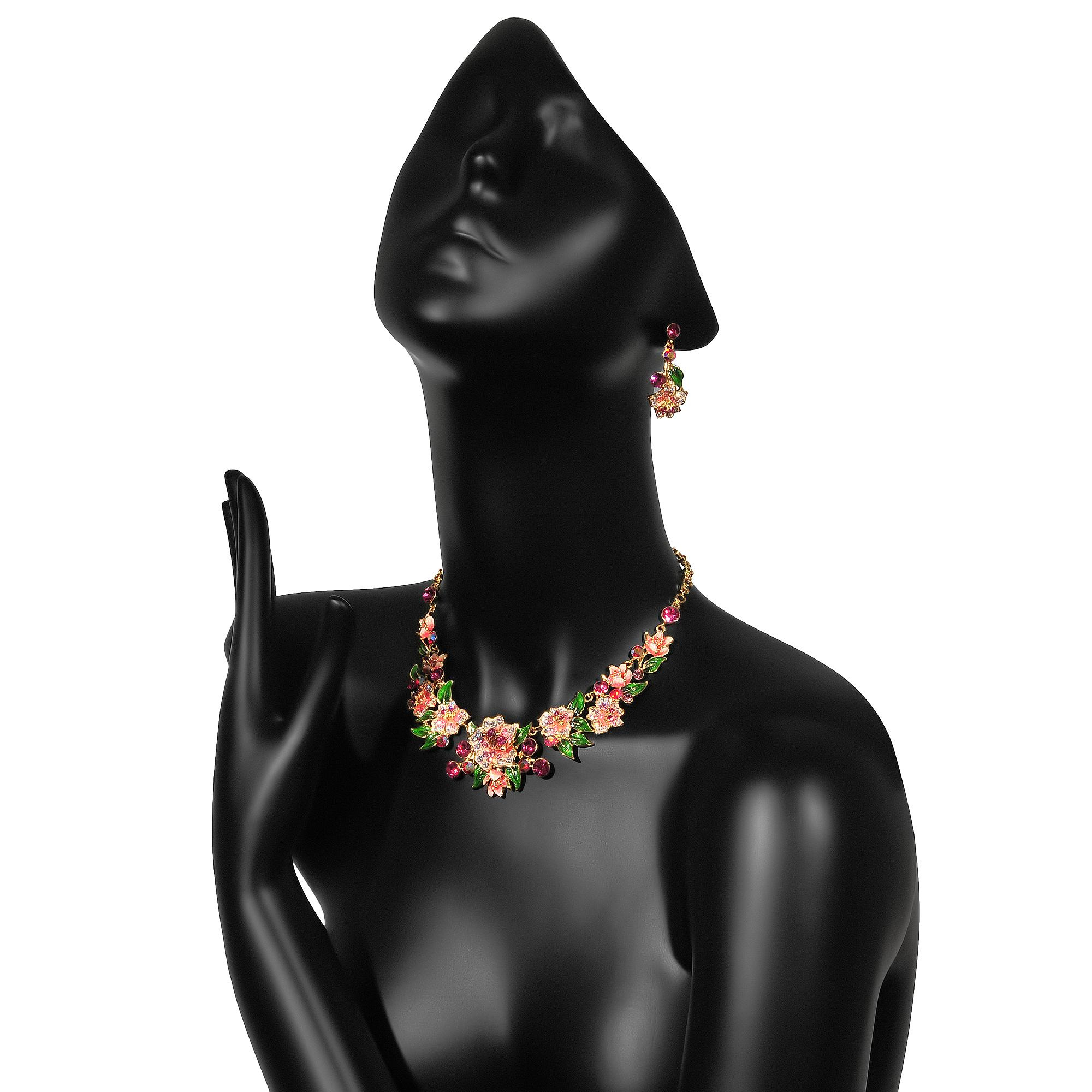 комплект бижутерии с цветами на черном глянцевом манекене на белом фоне