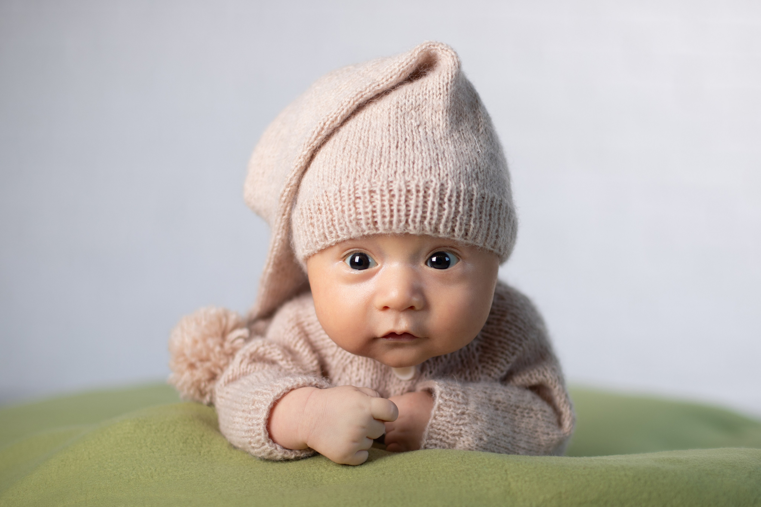 Милый малыш в вязаном костюмчике смотрит в кадр.