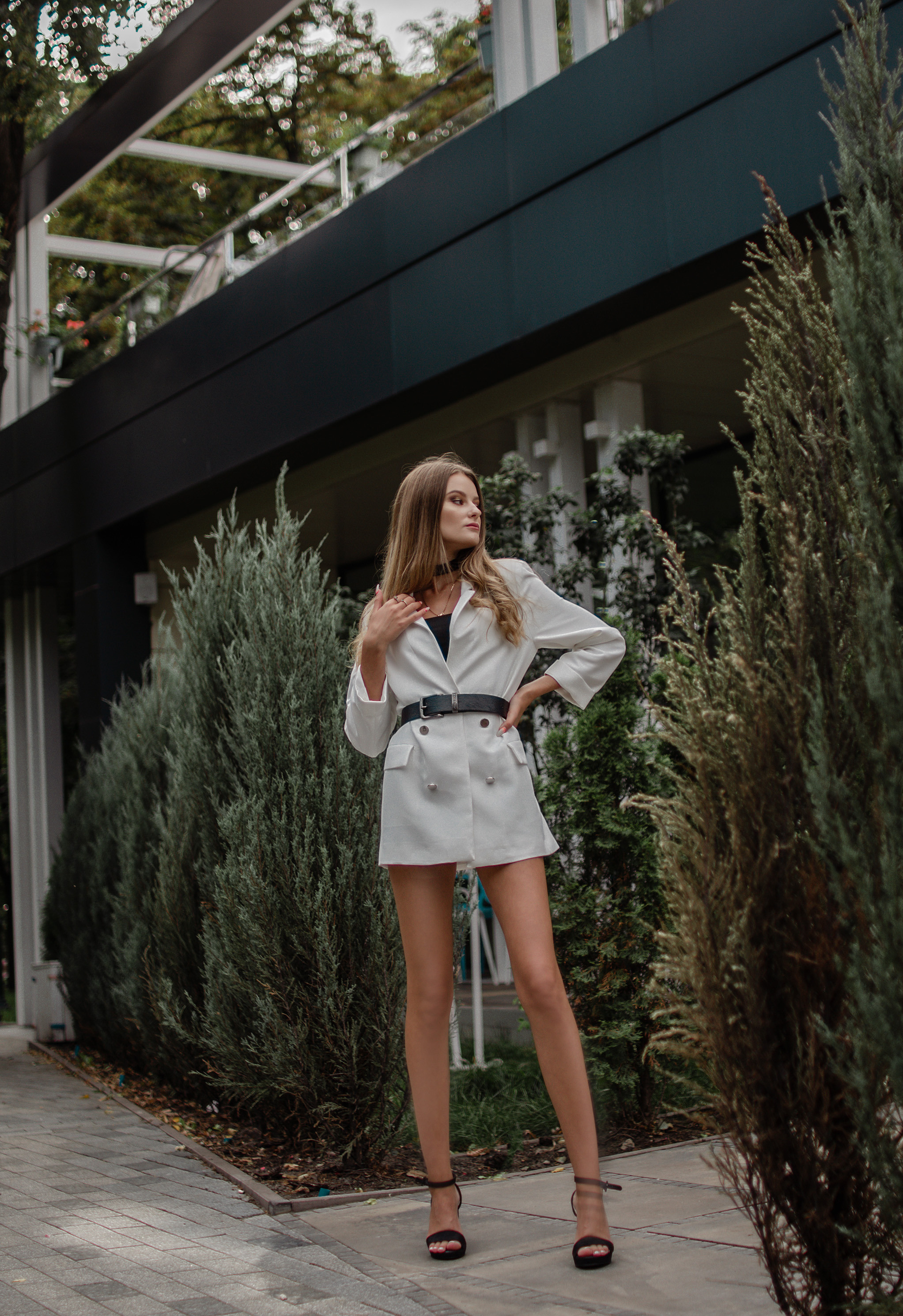 Стройная девушка с очень длинными ногами гуляет по городскому парку.