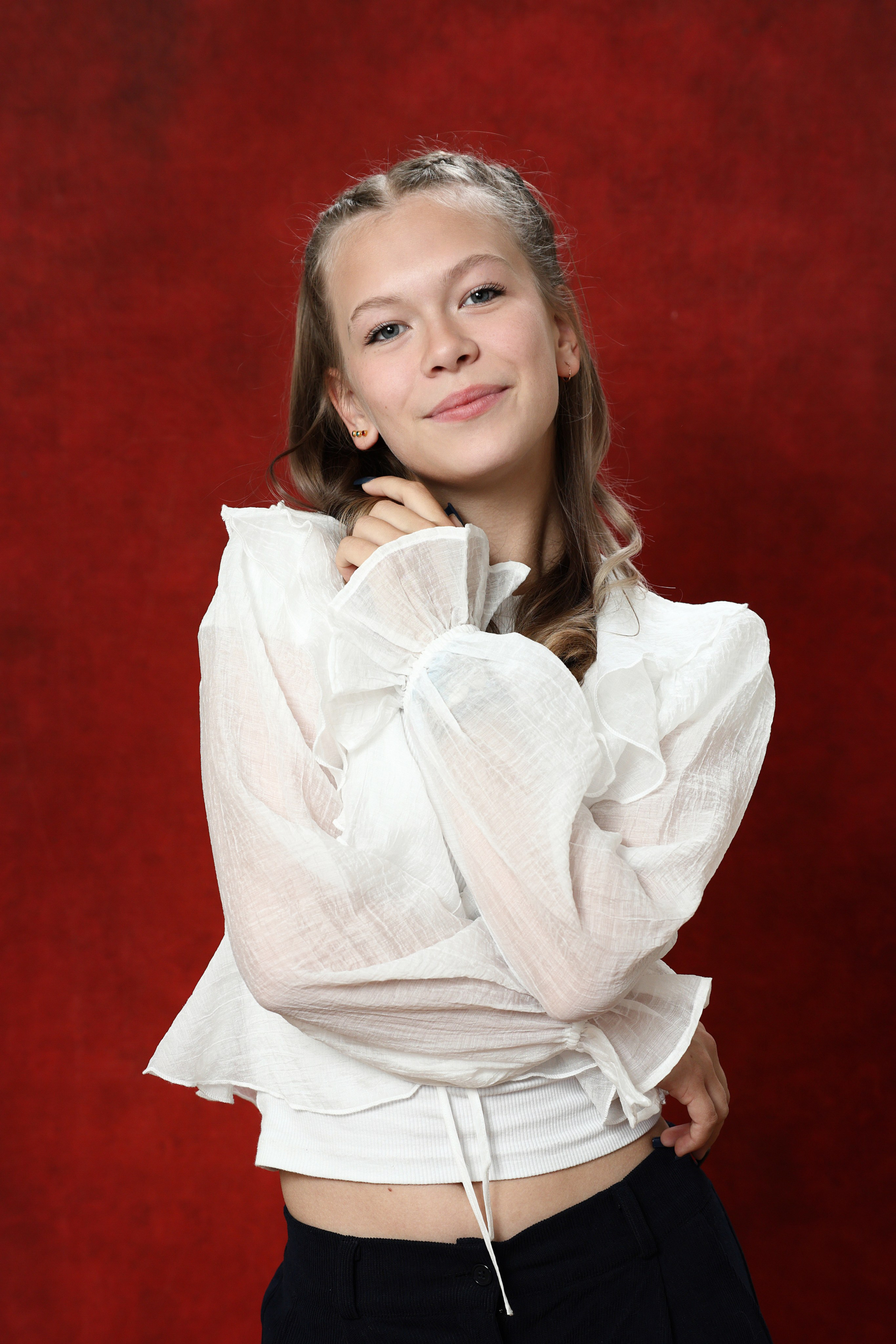 Поясной портрет ученицы в белой рубашке на бордовом фоне с мягким светом.