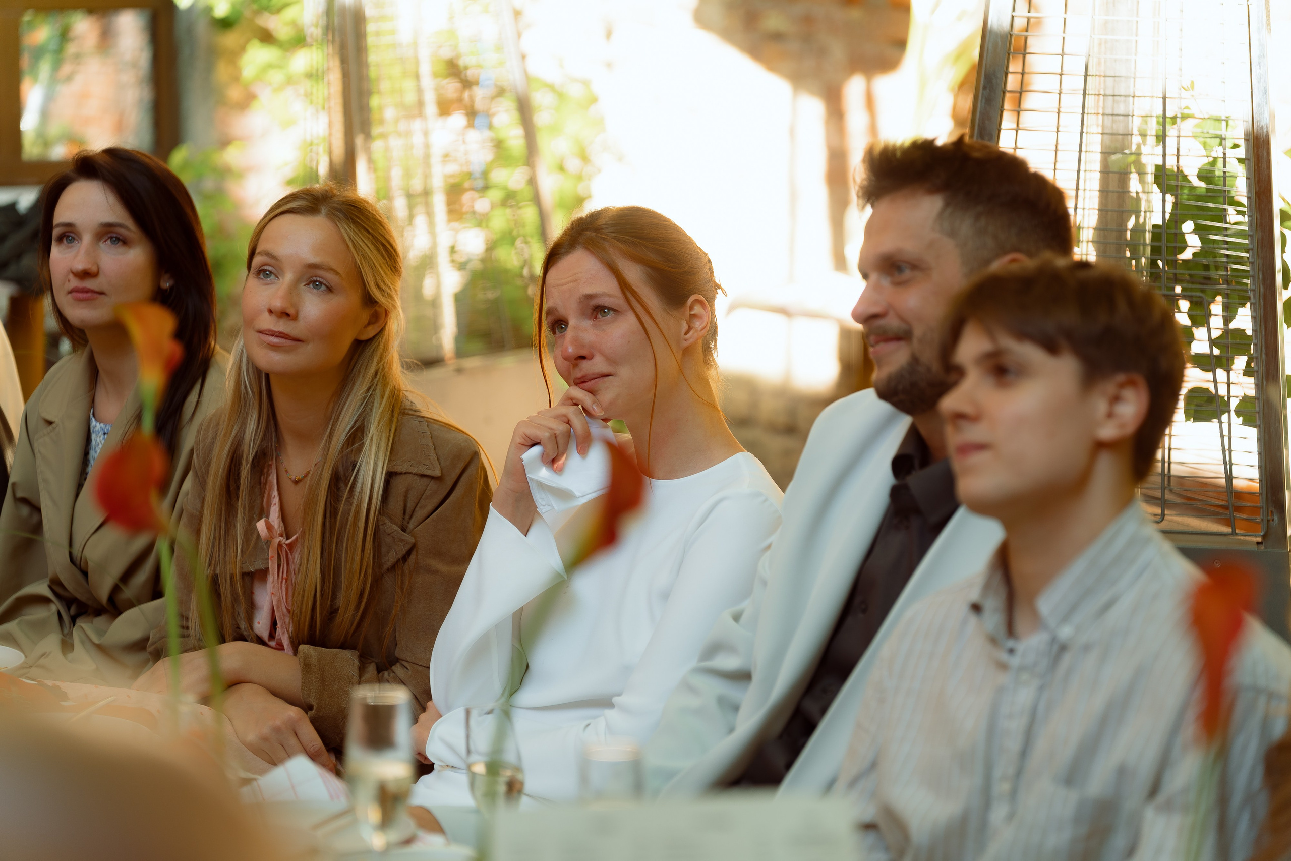 Ряд гостей внимательно слушают речь, лица в полутени
