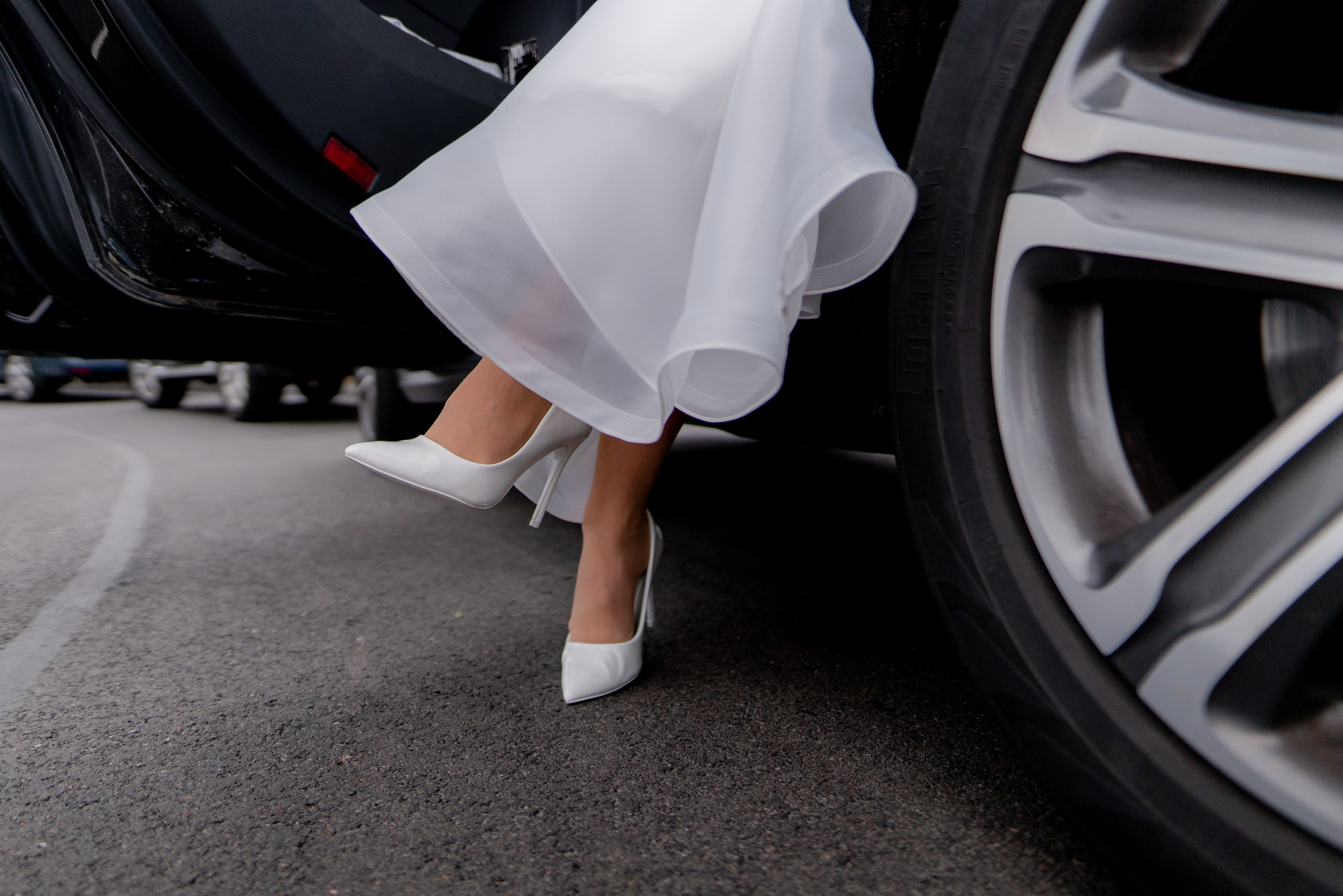 белые туфли невесты на фоне колеса свадебного автомобиля