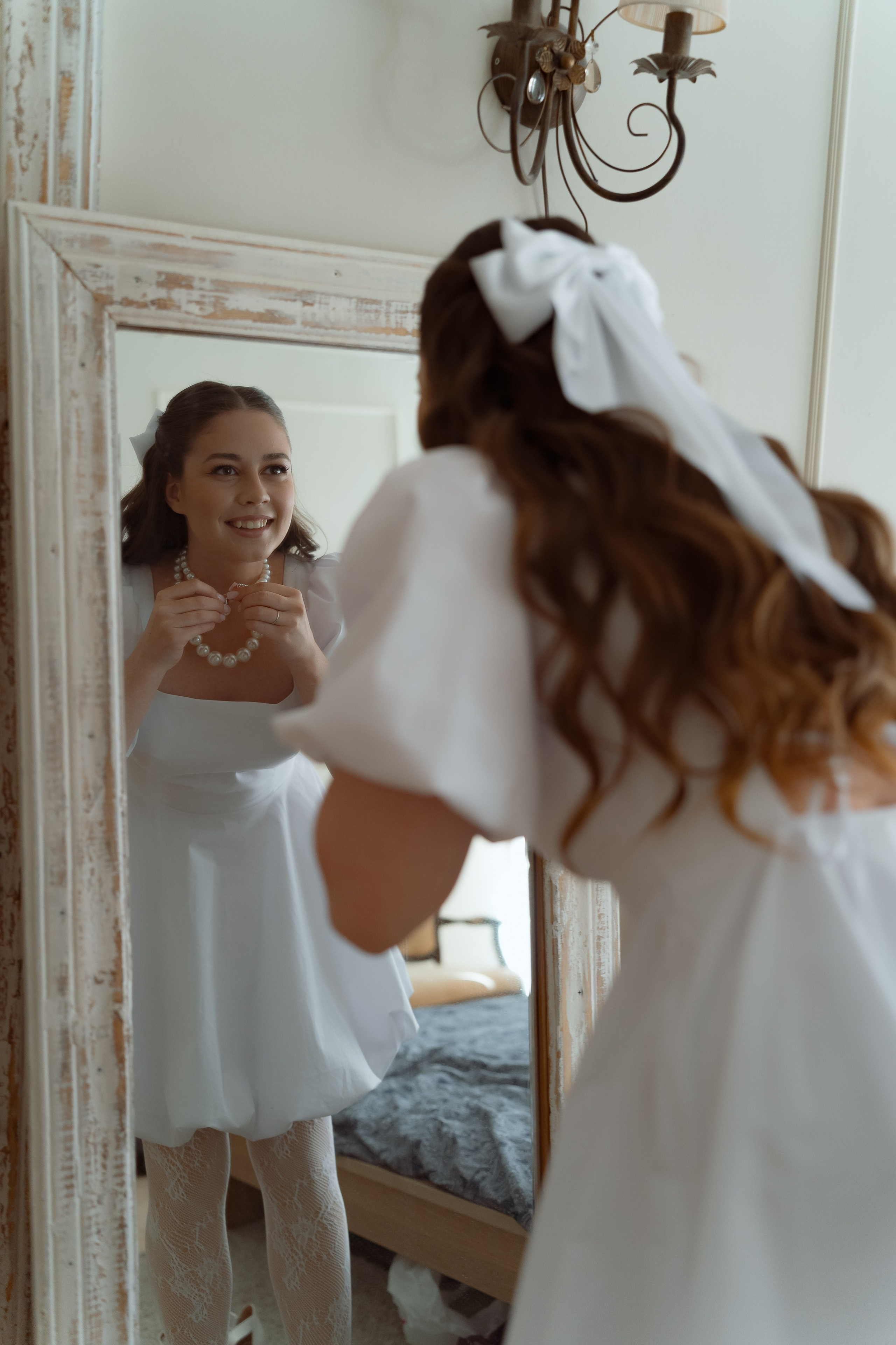 Невеста поправляет украшения перед зеркалом, утро невесты дома