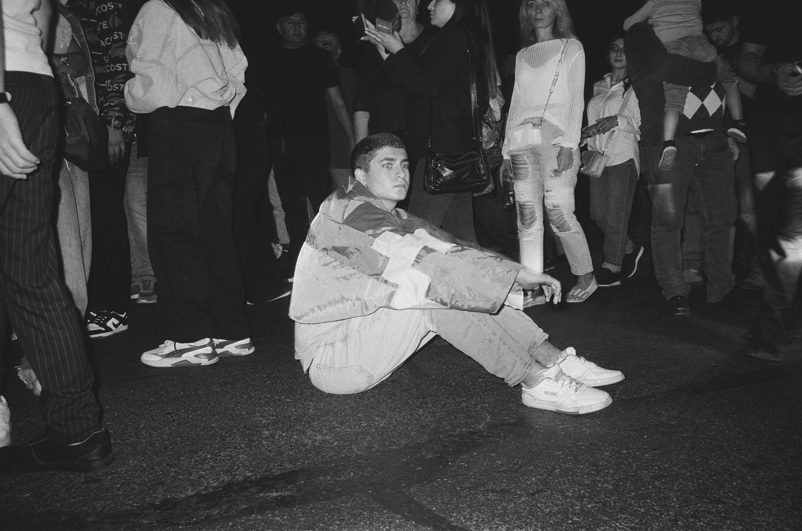 A young man sits on the road, blocking traffic for vehicles during the night-time street blockades